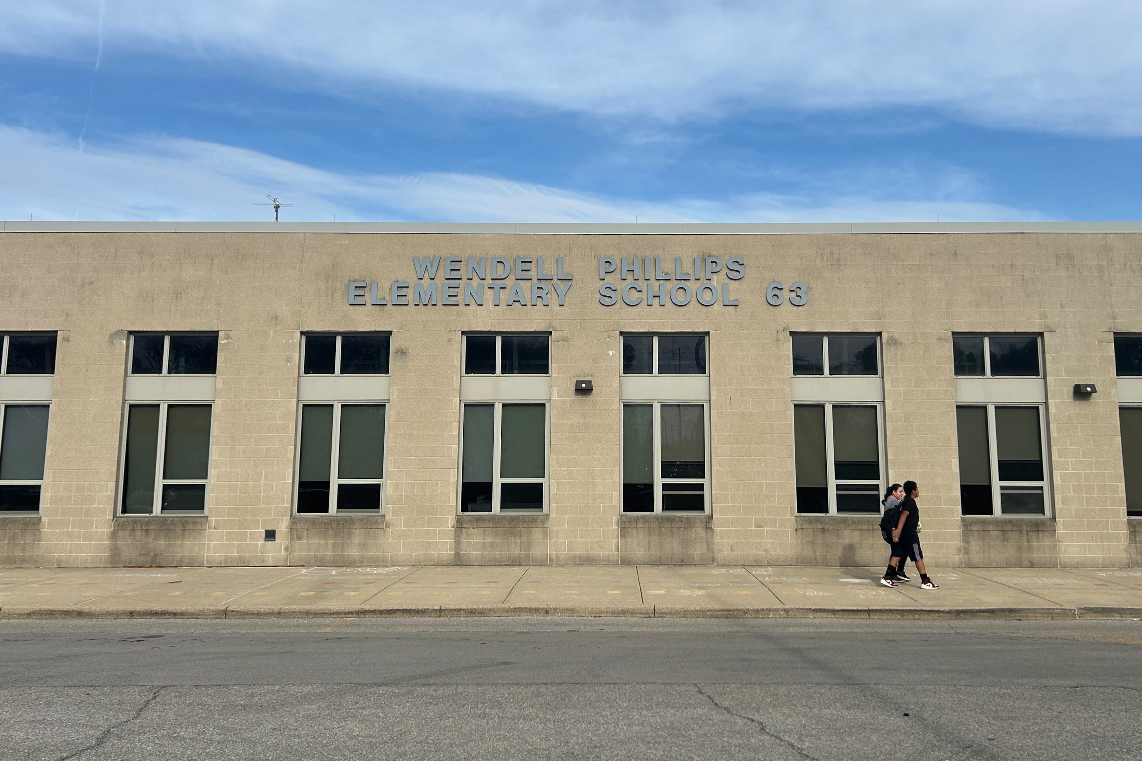 A person walks in front of a brick building.