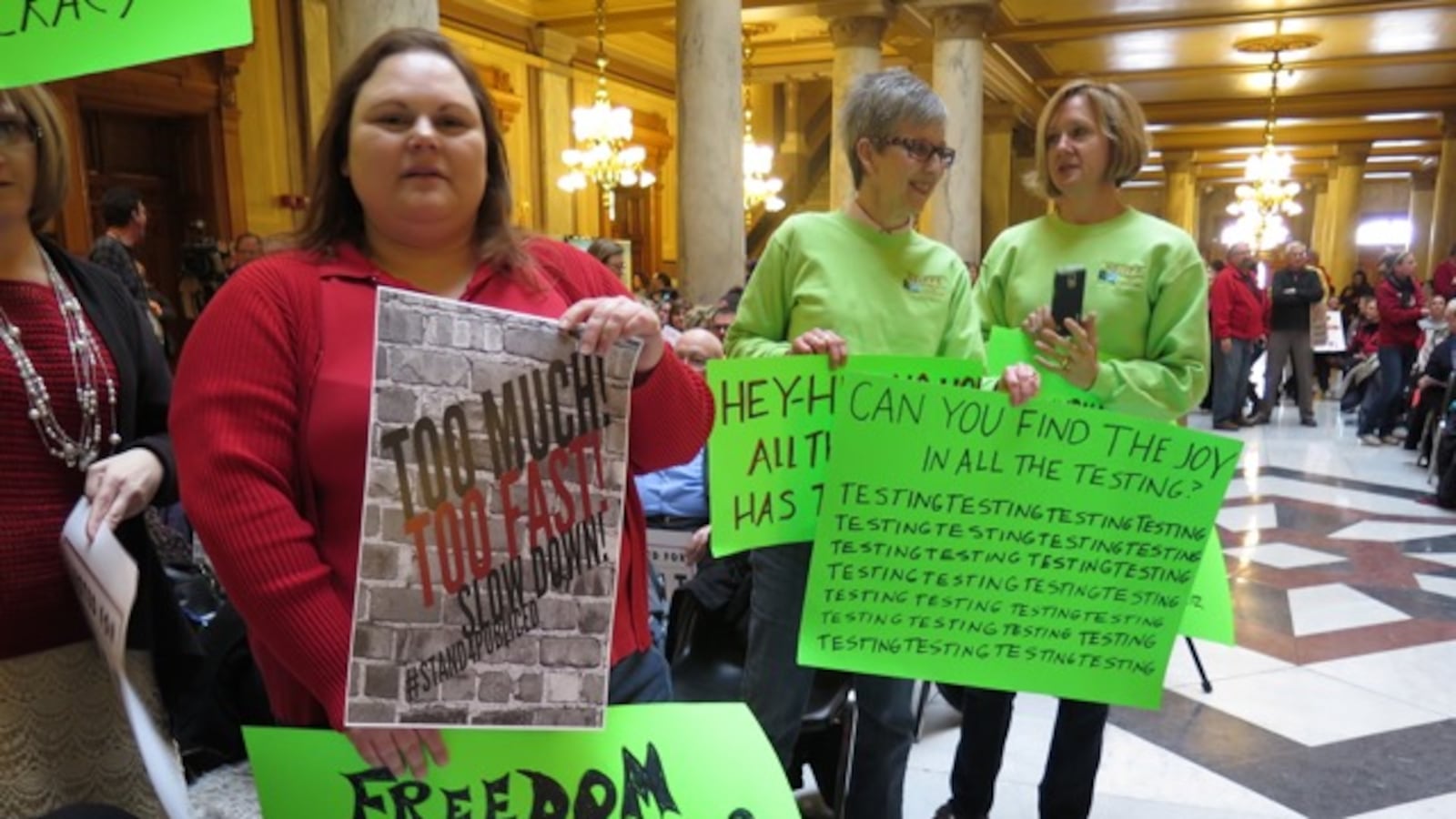 Protesters hold signs criticizing testing and other concerns at a union-led rally at the statehouse last February.