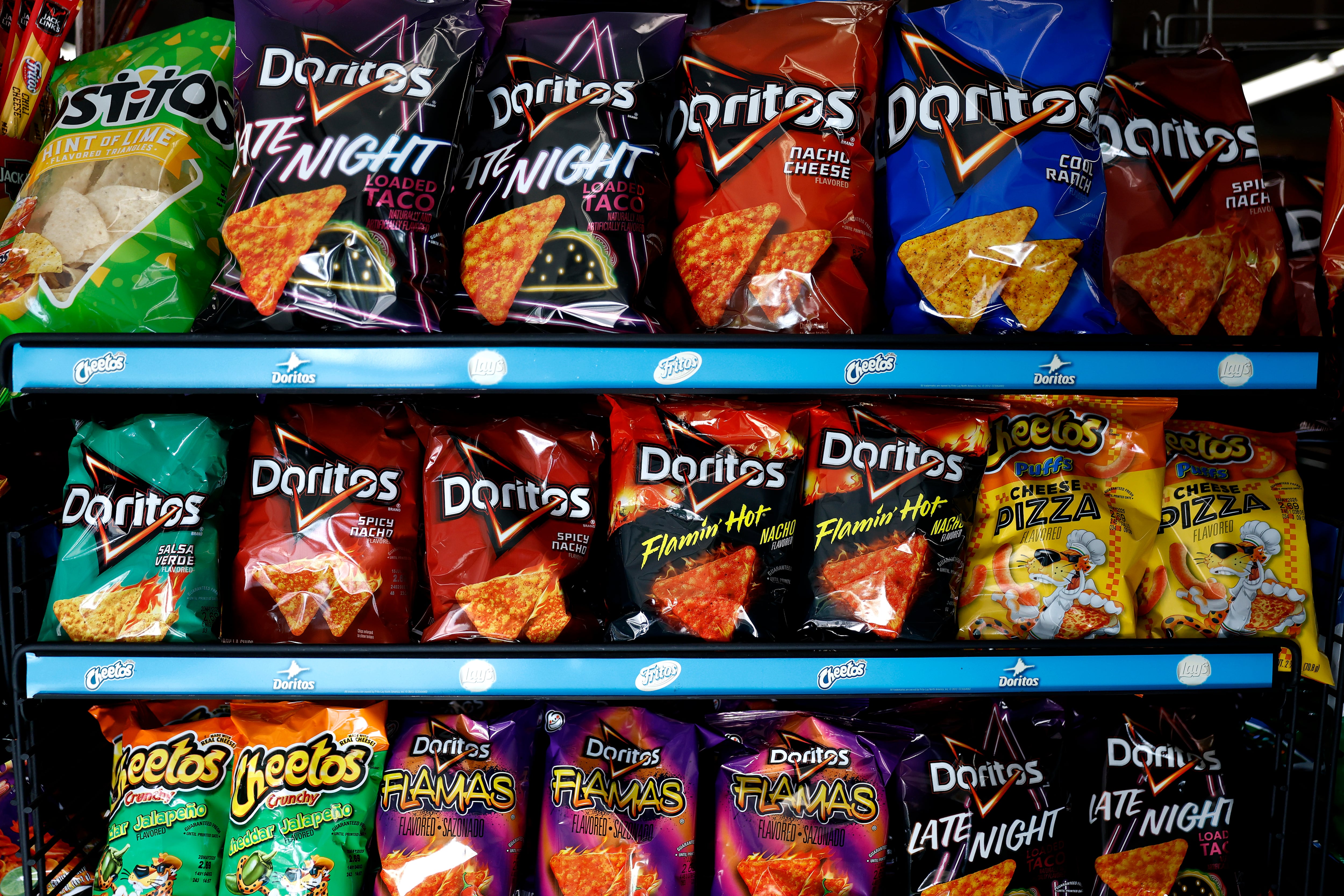 Packages of Doritos and Cheetos are displayed on a store shelf.