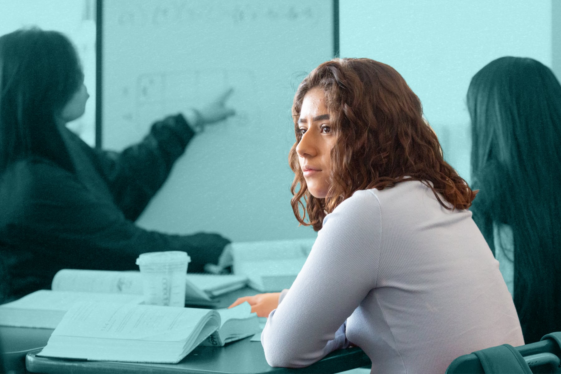 A student looking away from a whiteboard with math problems written on it.