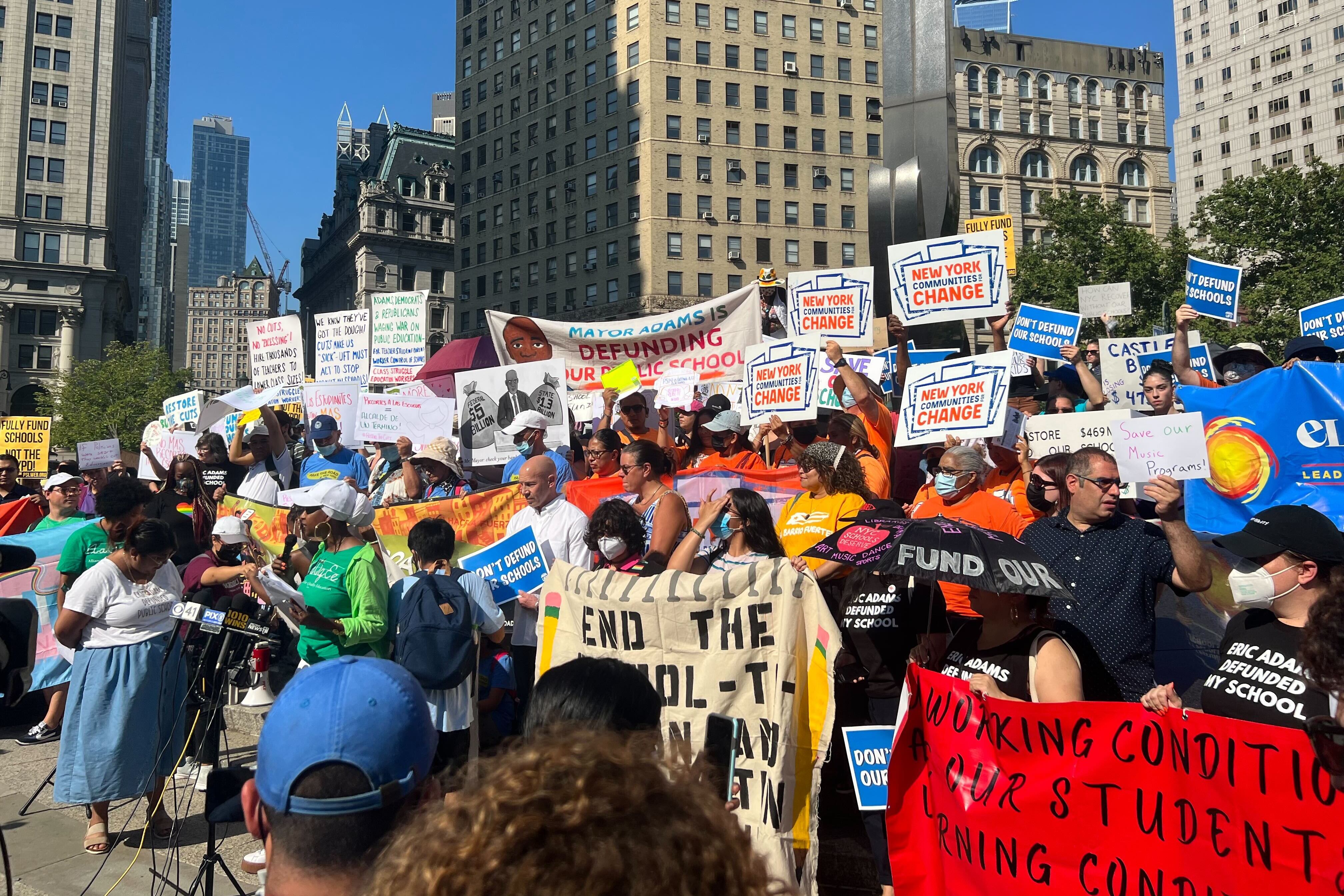 A large crowd of parents and education advocates holding signs of protest crowd the stairs of a Manhattan courthouse.