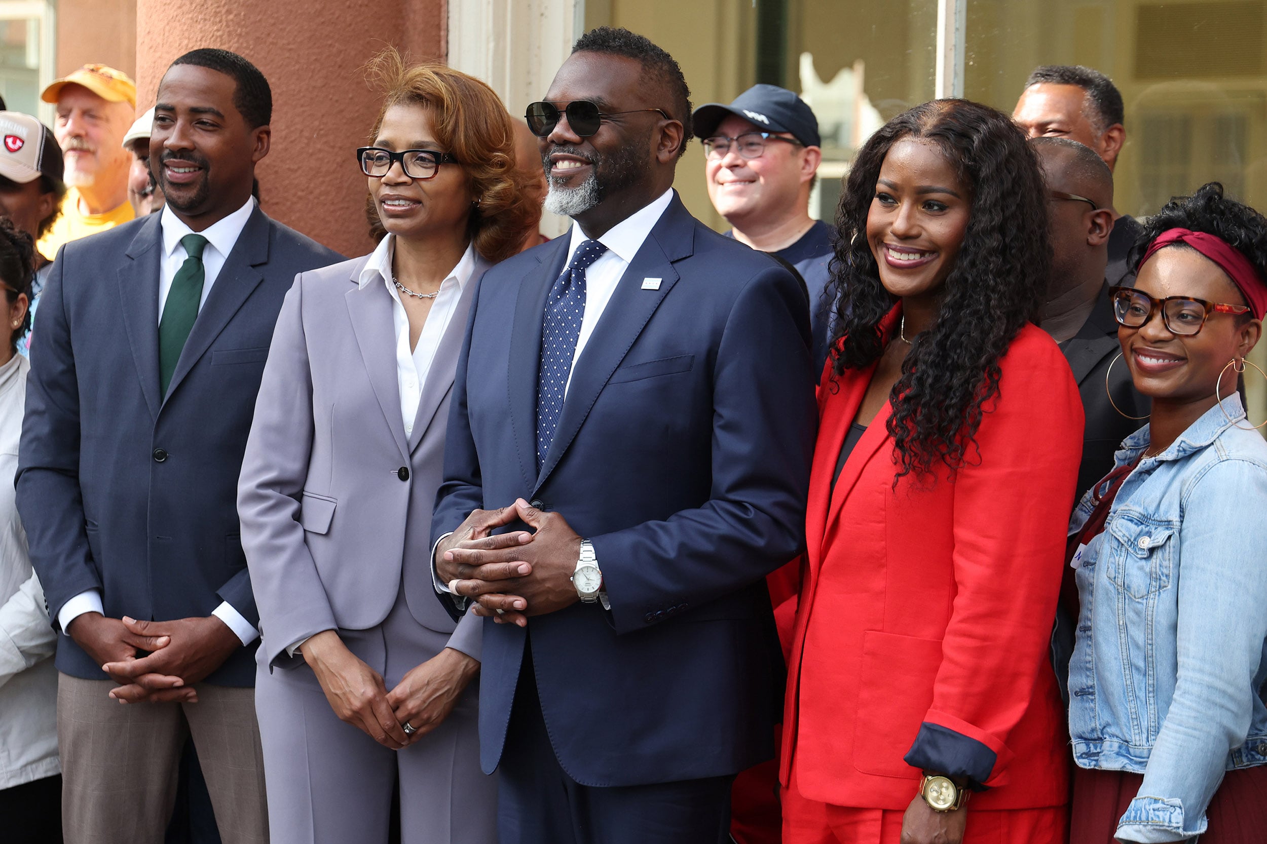 A photograph of a group photo showing five Black adults in suits standing next to each other in a larger group.