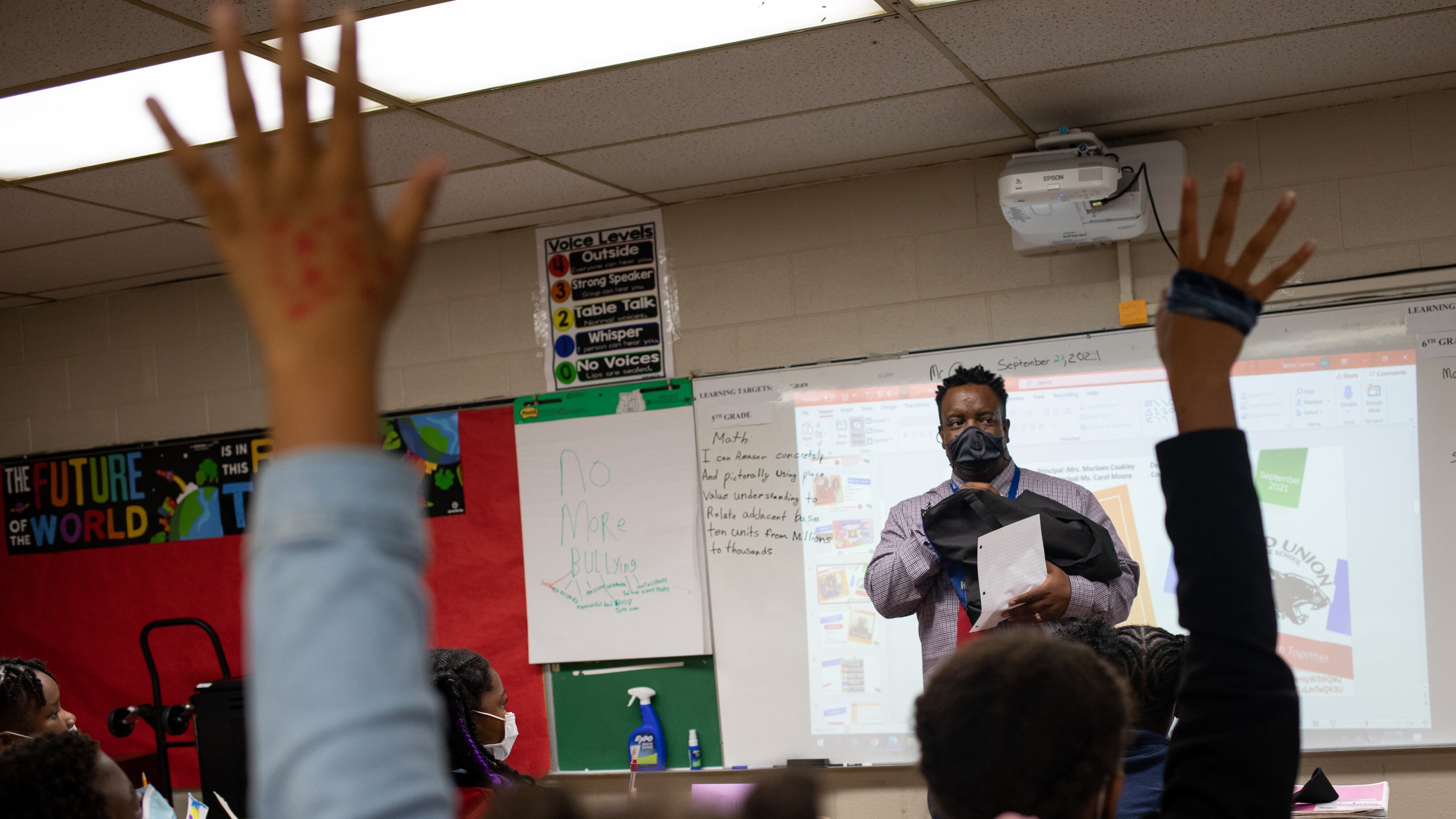 Students raise their hand in a classroom.