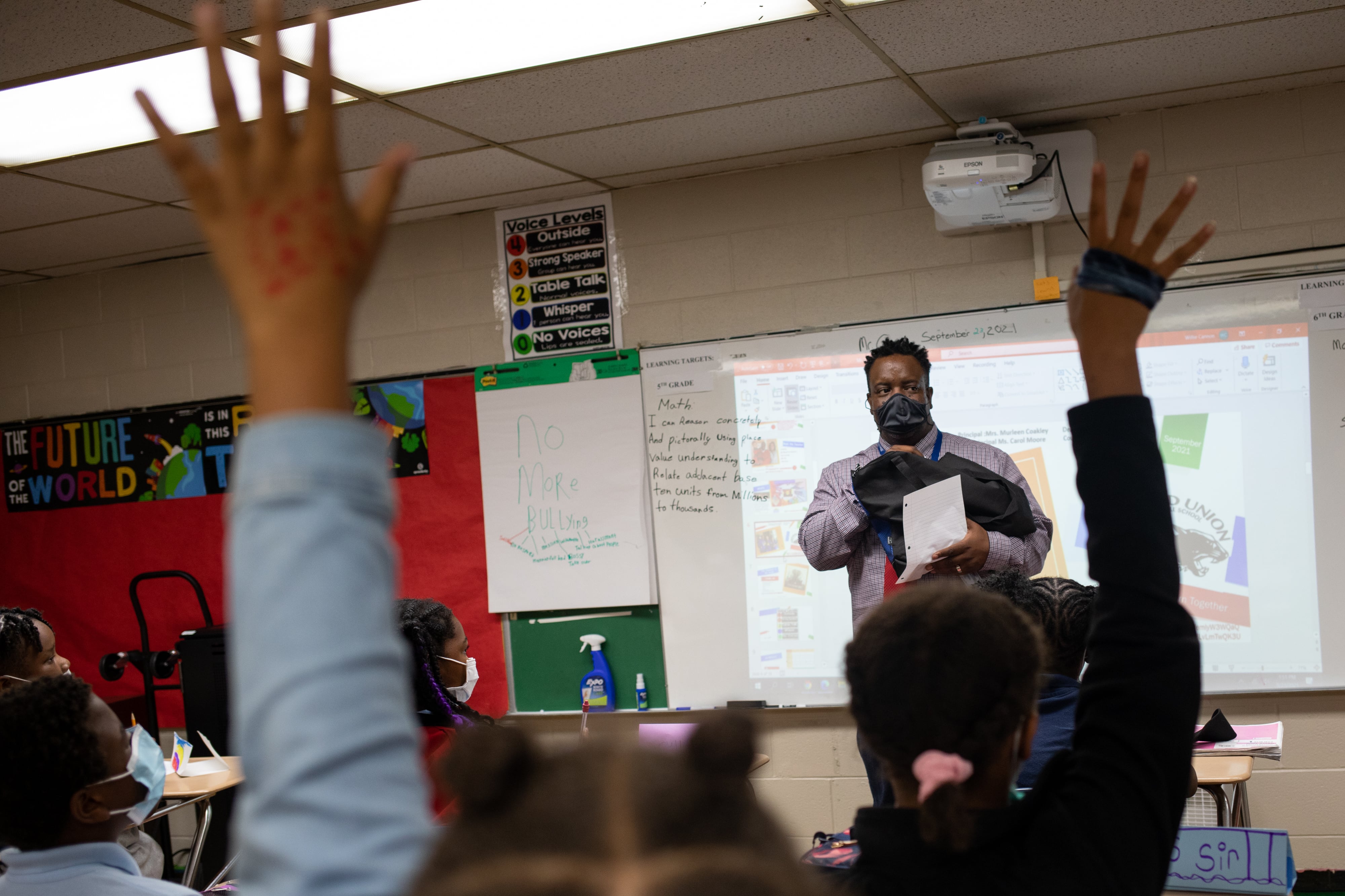 Students raise their hand in a classroom.