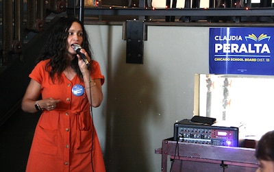 A woman in a red dress speaks into a microphone.