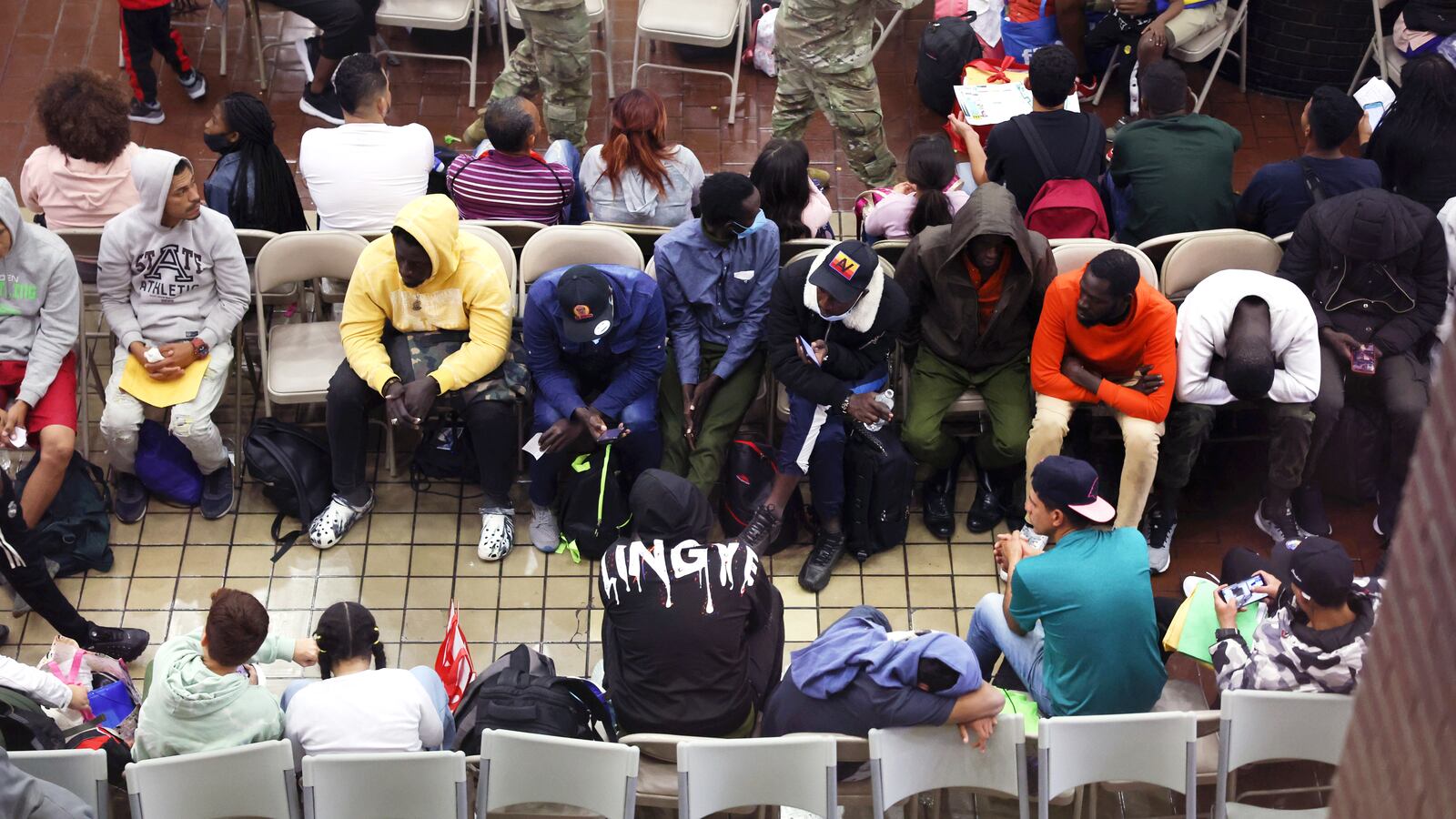 Lots of people sit crowded in chairs waiting to be relocated