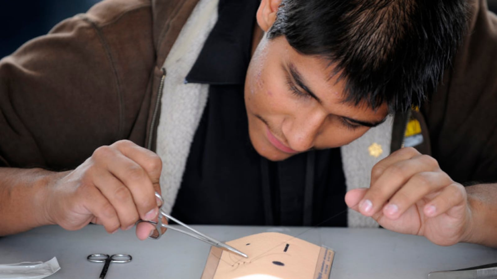 Health care professions are the focus of IDEA's first school attempting the diverse-by-design model. Pictured is a student practicing how to make sutures at a health careers expo in Colorado.