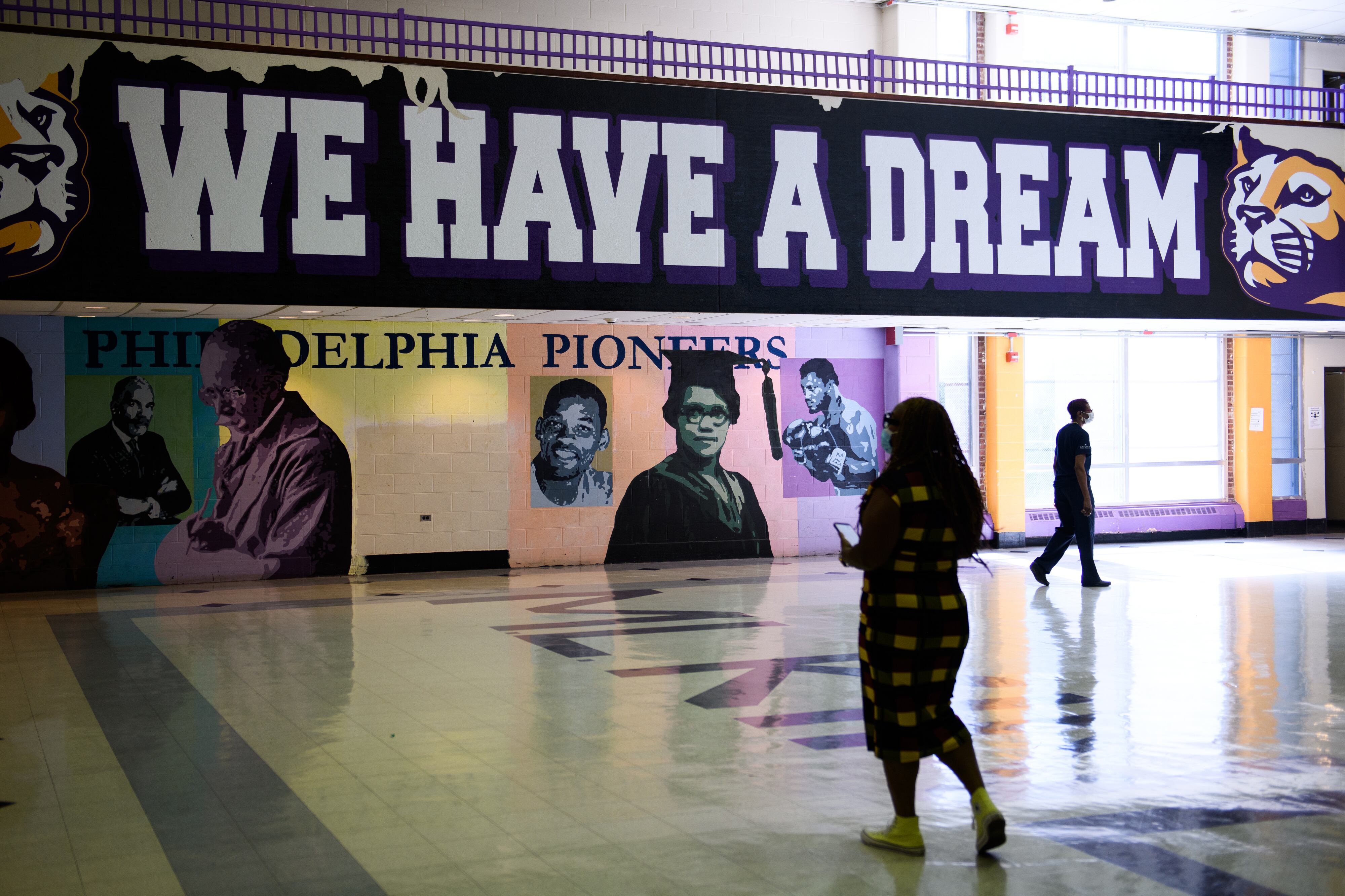 A school official walks in front of a sign in a cavernous hall that reads “We Have a Dream.”