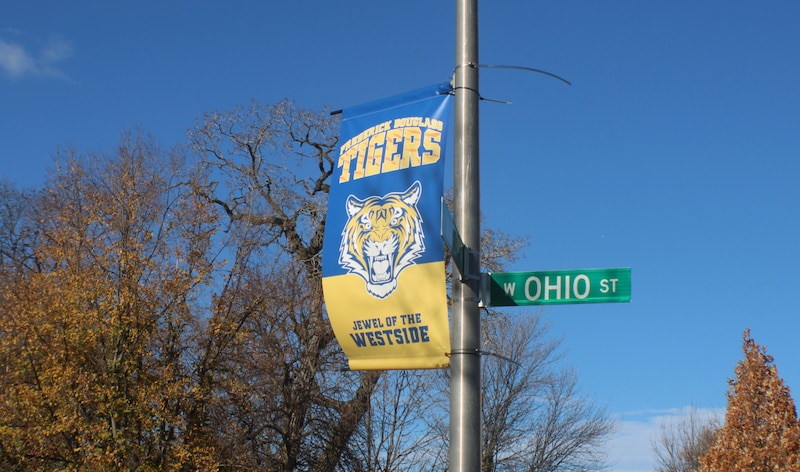 A street sign pole shows a flag with a school mascot of a tiger and also a street sign with the name " Ohio st"