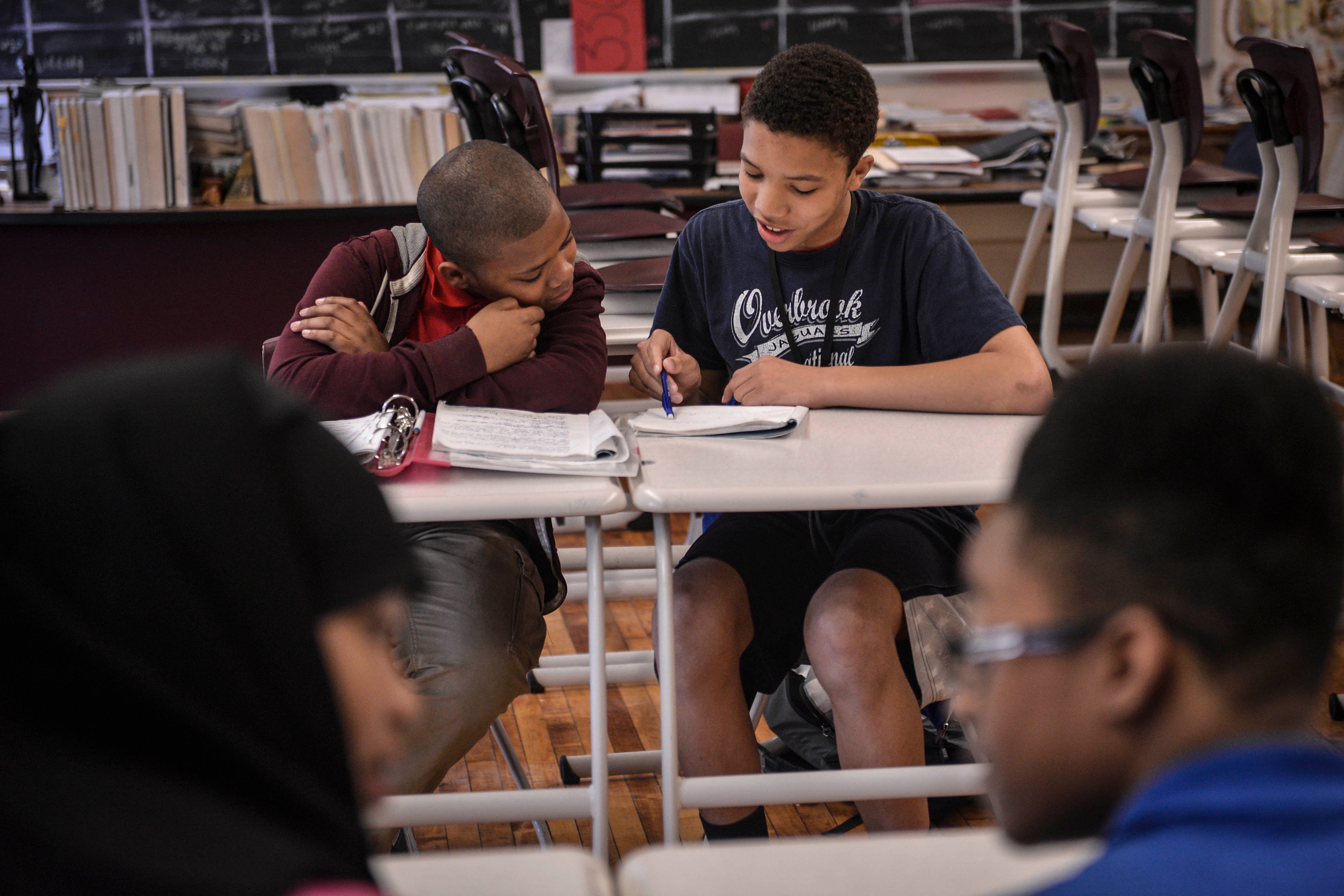 Two students read a book at a desk