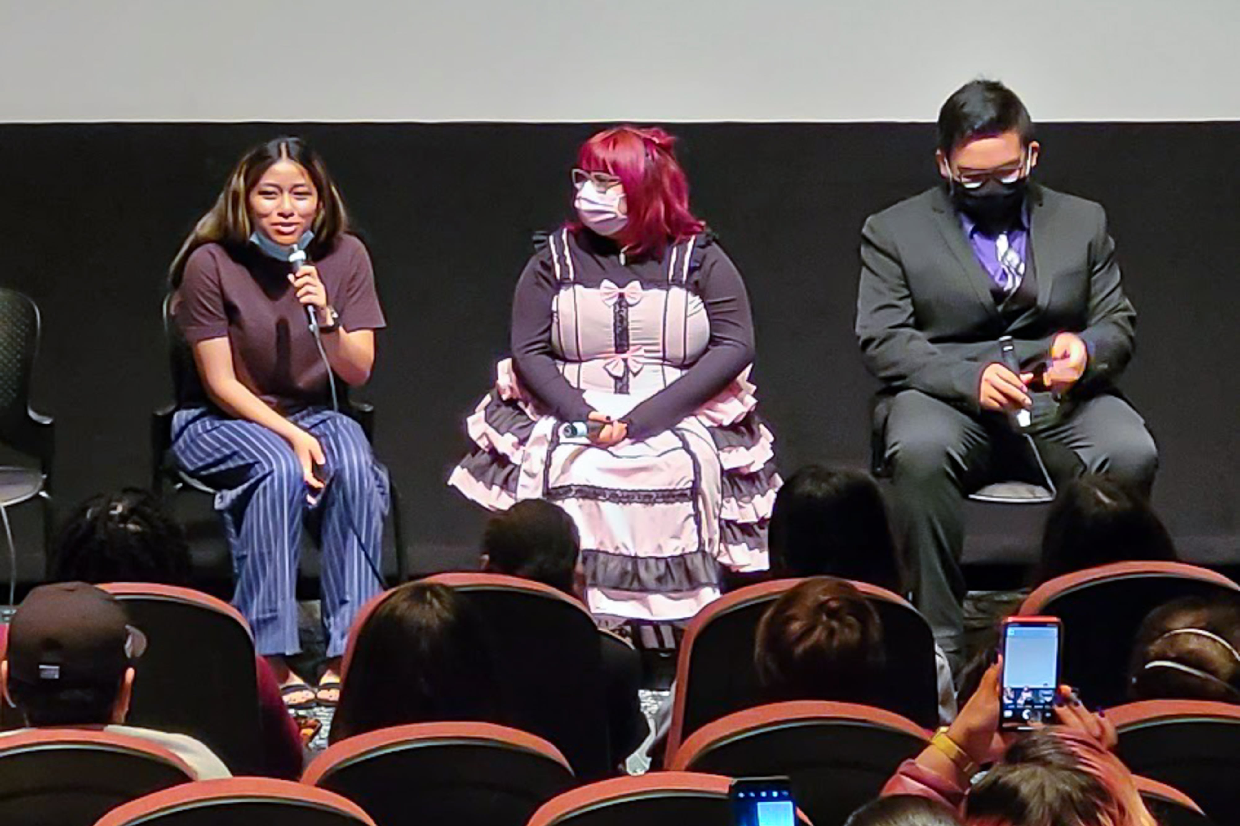 Three students sit on a stage in a movie theater auditorium during a screening of their student film at a May 4 screening at Gene Siskel Film Center in Chicago.
