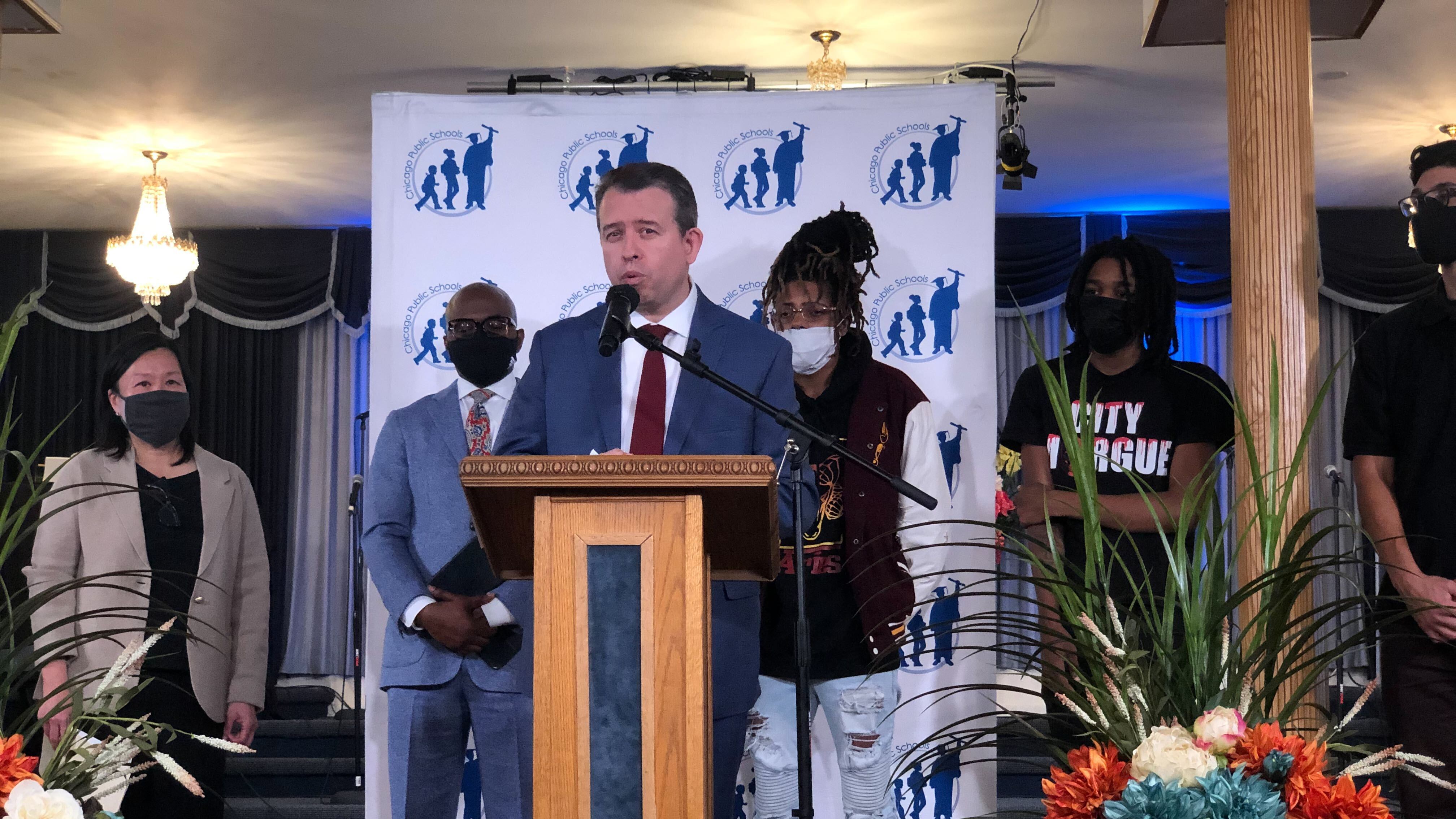 Flanked by district officials and local students, Chicago Public Schools CEO Pedro Martinez stands at a podium in a suit and tie and announces an expansion of a youth violence intervention program Choose for Change.