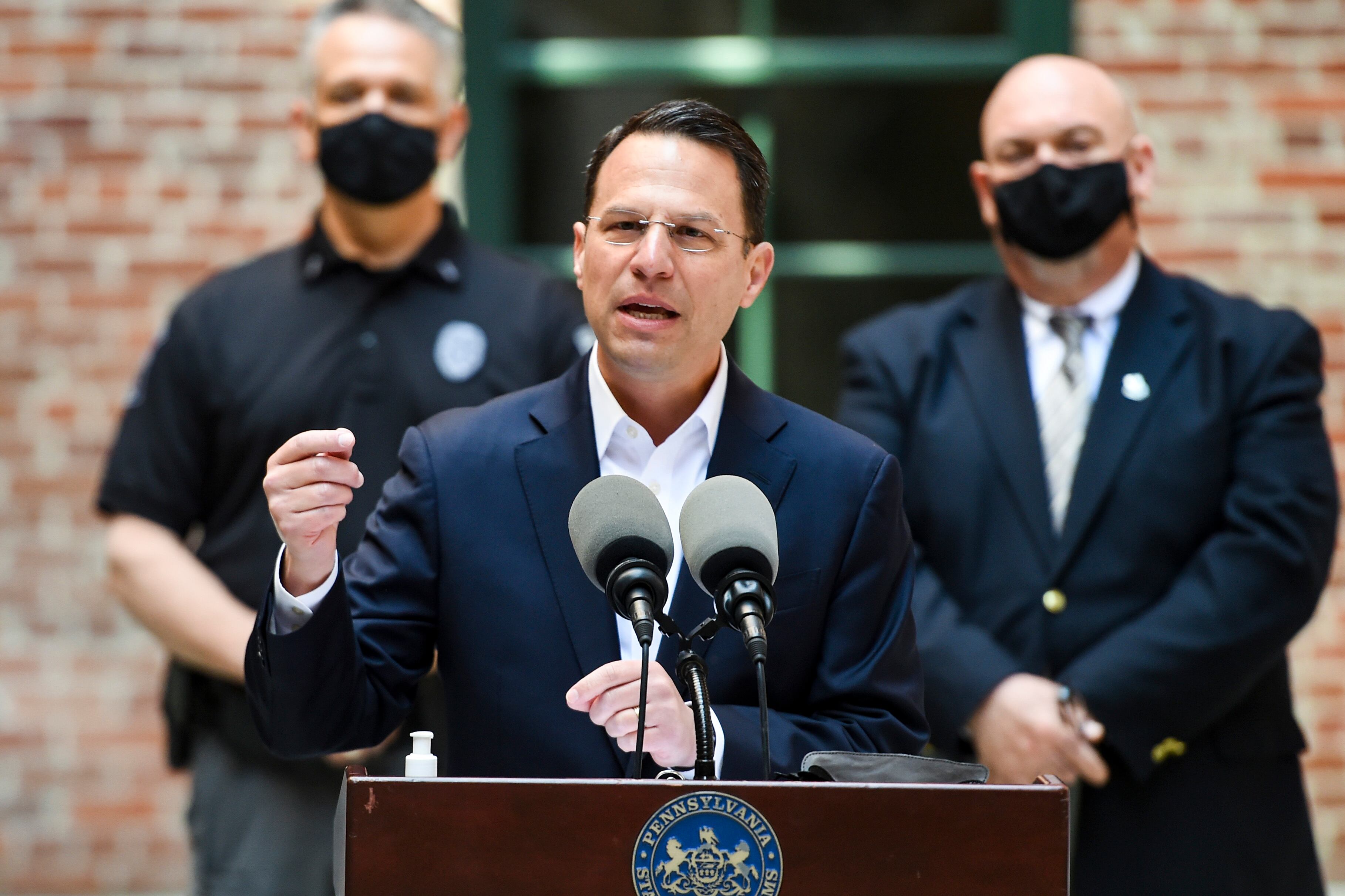 State Attorney General Josh Shapiro makes hand gesture while speaking at a podium.