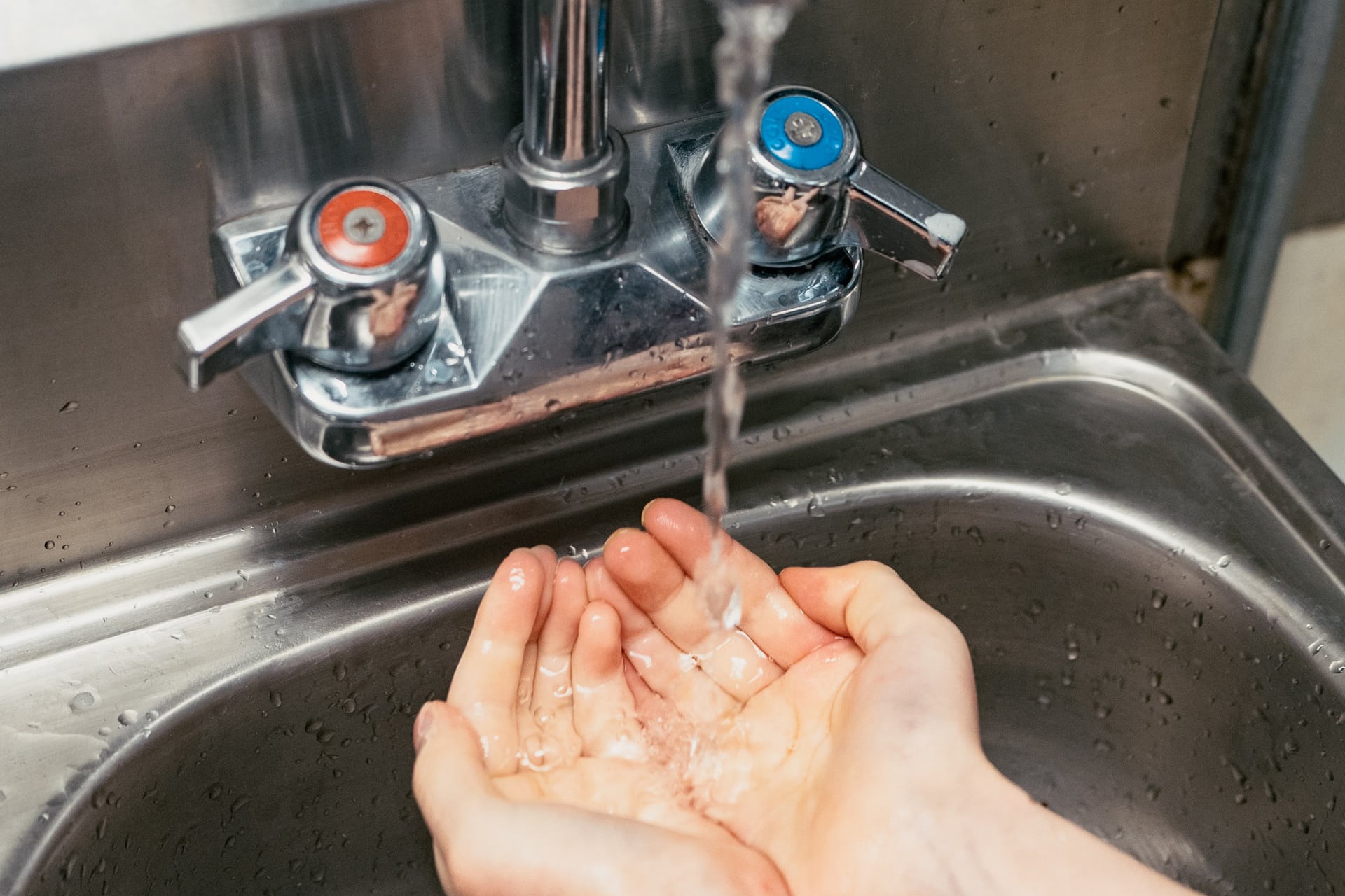 Close up of a person washing their hands in the sink.