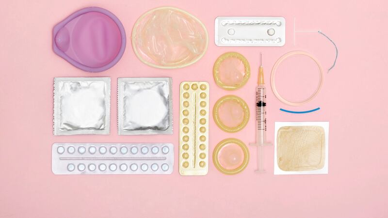Various contraception items rest against a pink background.