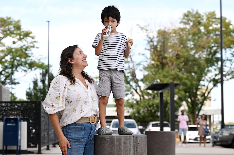 A woman and a young boy pose for a photograph outside.