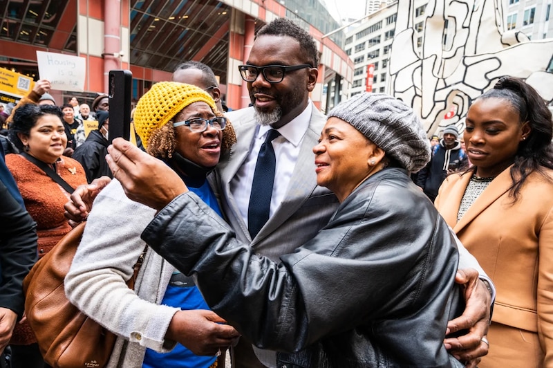 Mayor Brandon Johnson hugs two women outside the Thompson Center in downtown Chicago.