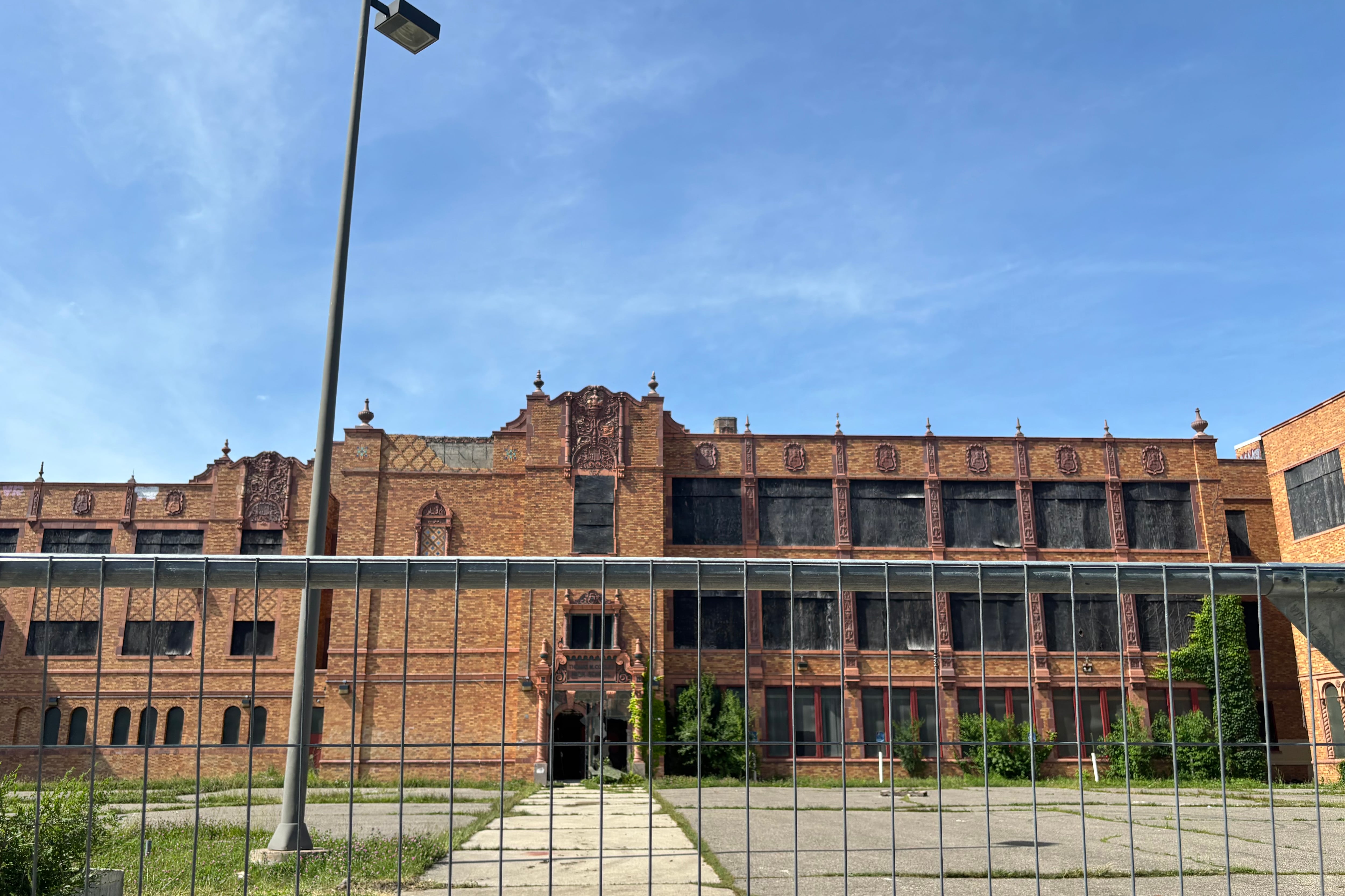 A photograph of a large abandoned high school building on a sunny day.