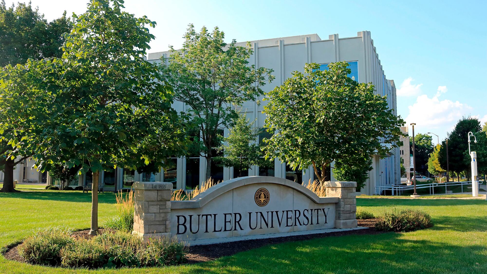 Outside sign that says Butler University with trees around it and building in the background