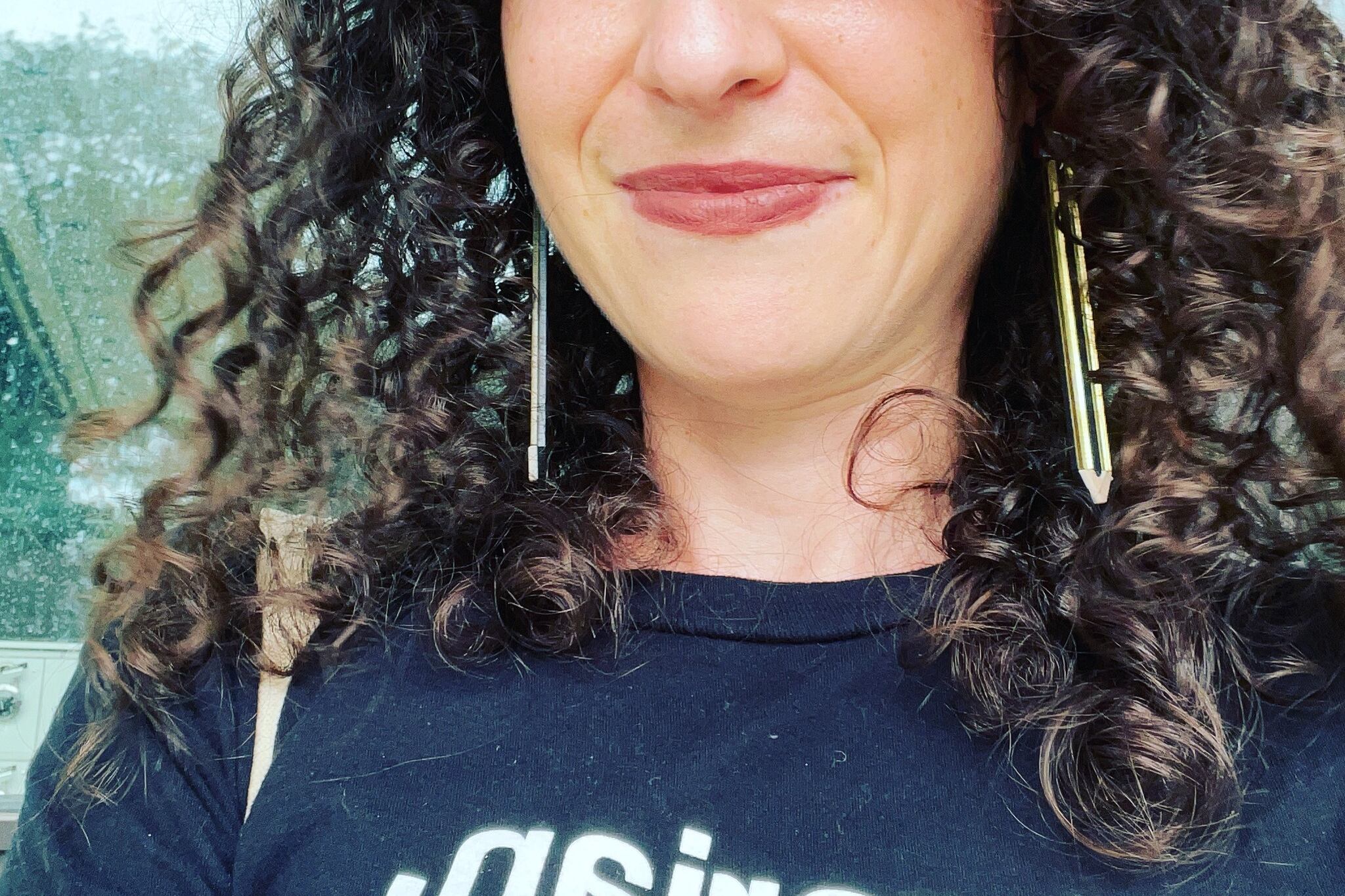 A white woman with curly hair smiles at the camera.