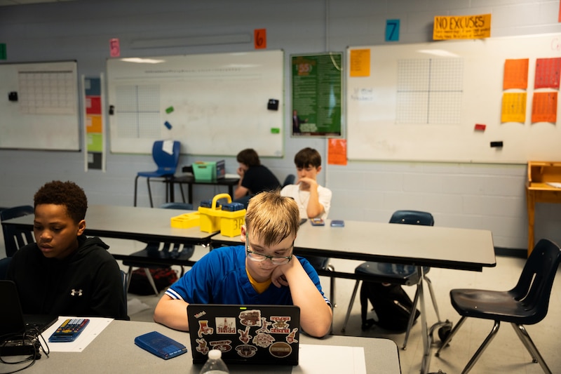 Children sit at tables in a classroom.