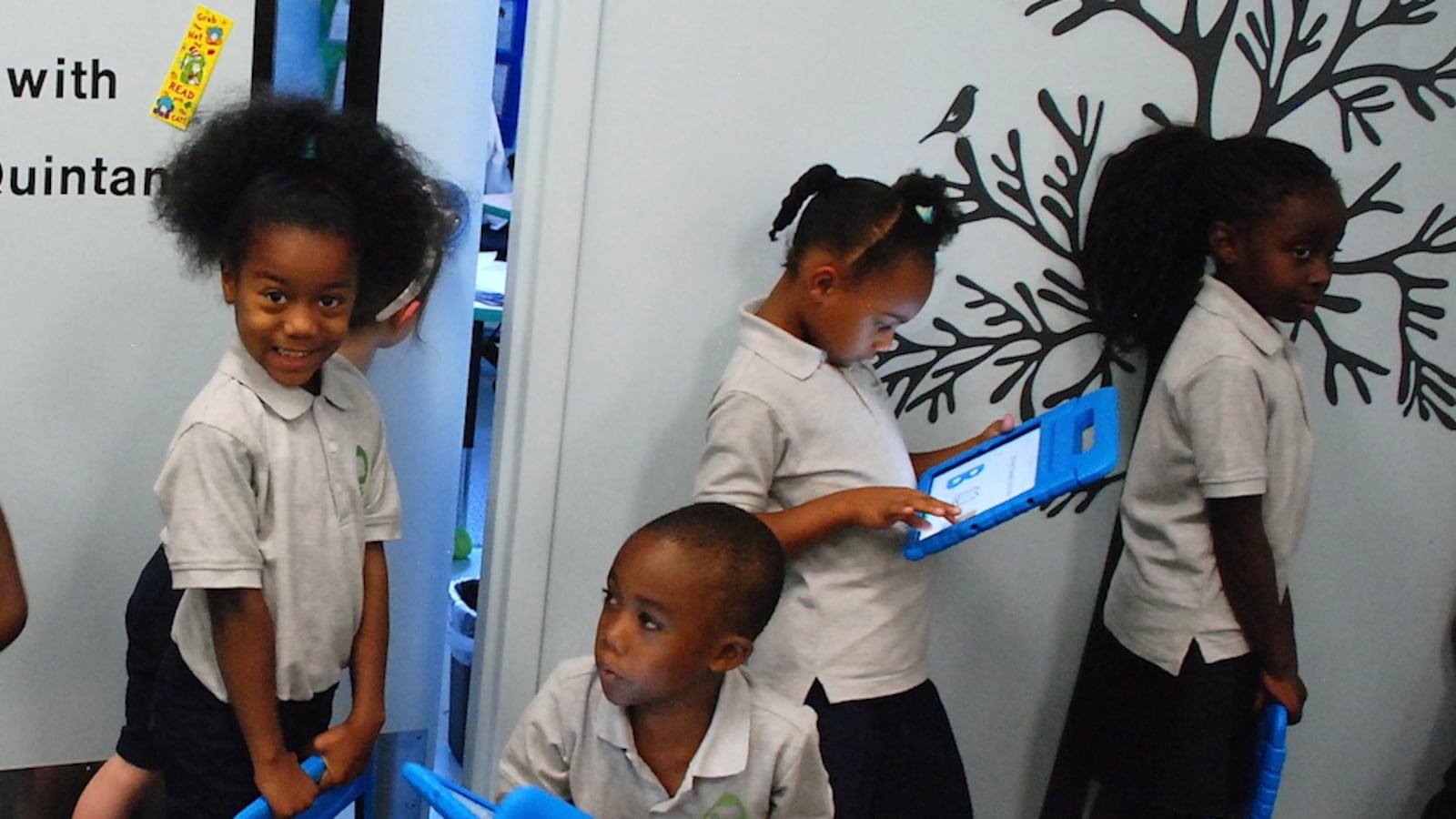 Roots Elementary students hold iPads as they stand in line to go into one of the school's mini-classrooms.