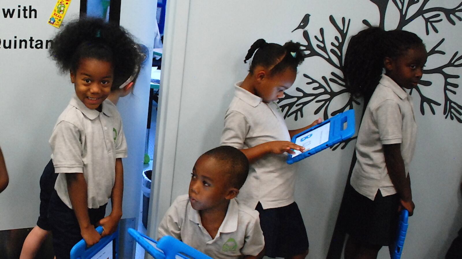 Roots Elementary students hold iPads as they stand in line to go into one of the school's mini-classrooms.