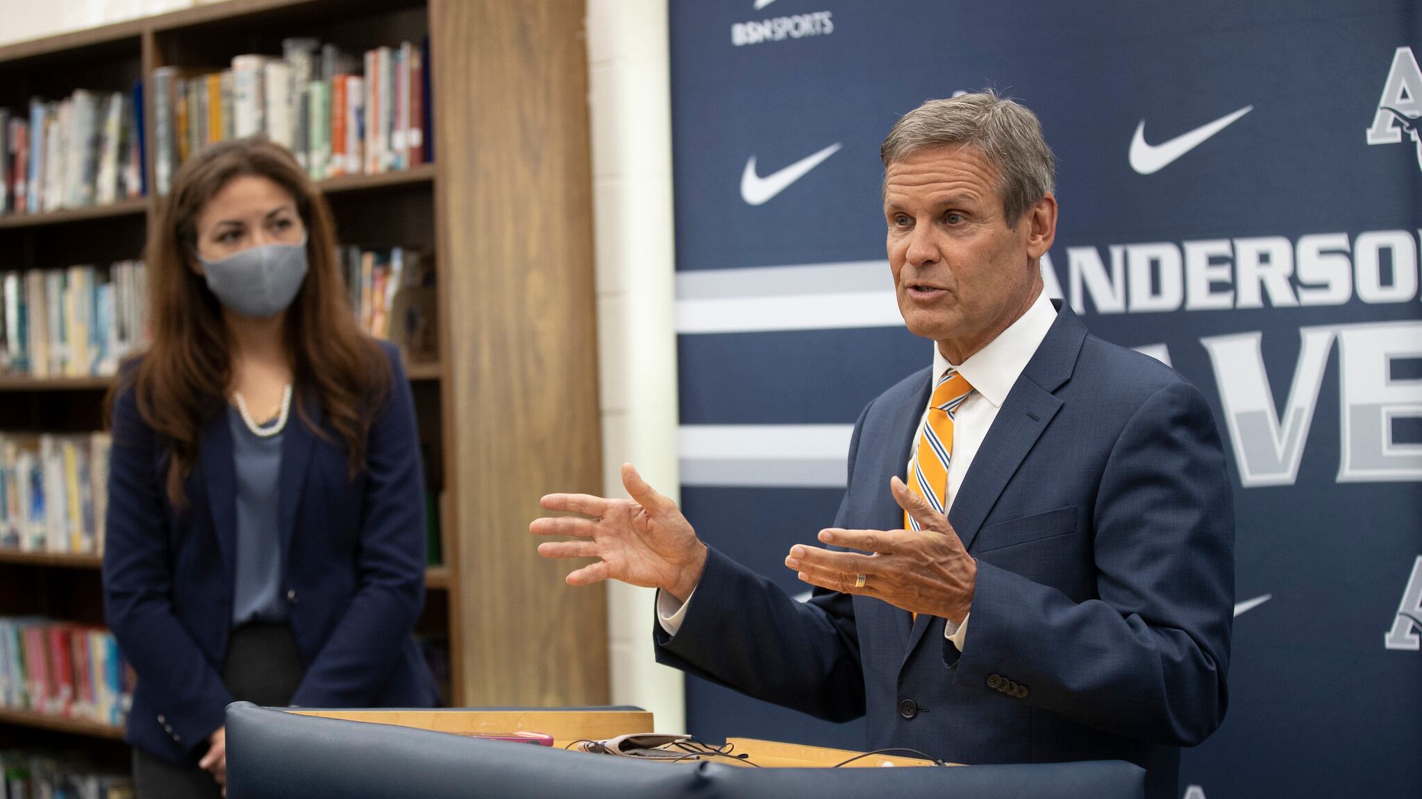 Gov. Bill Lee speaks at a podium while Tennessee Education Commissioner Penny Schwinn looks on