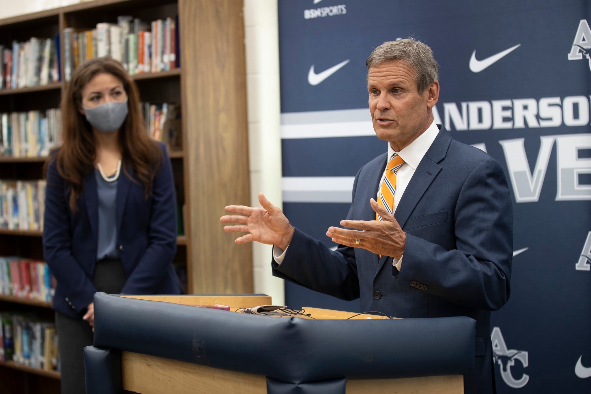 Gov. Bill Lee speaks at a podium while Tennessee Education Commissioner Penny Schwinn looks on