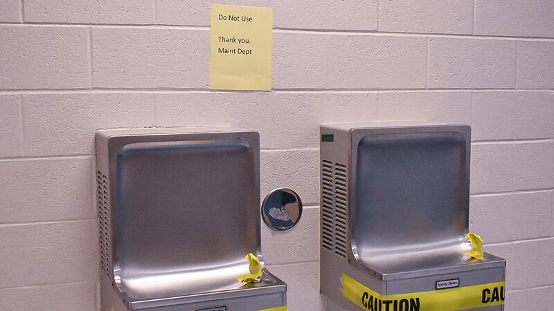 Two wall-mounted water fountains are marked with caution tape to prevent use.