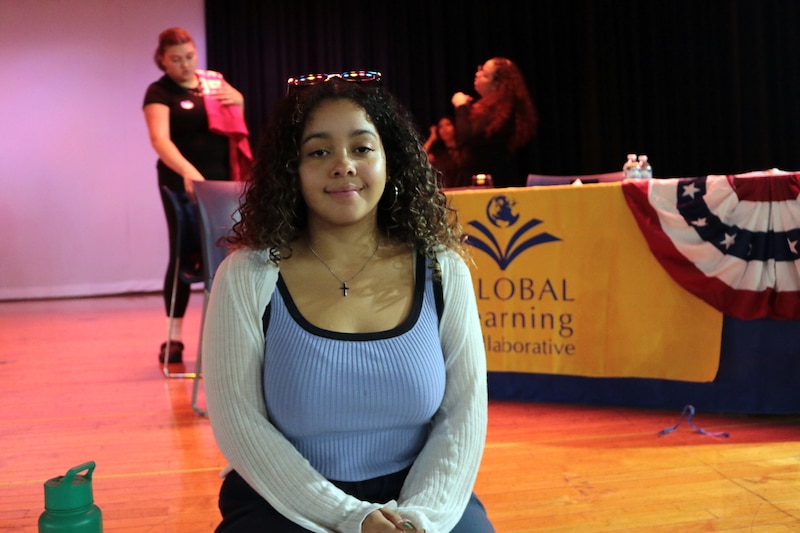 A student poses for a portrait in side of a school.