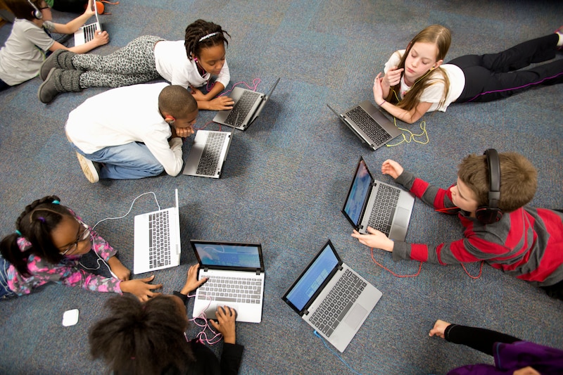 Overhead photo of students lying on the floor and working on their computers.