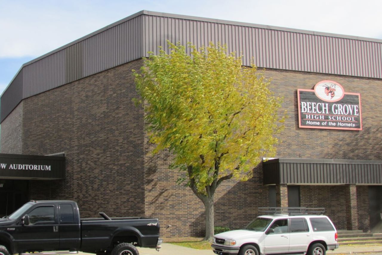 Two large vehicles parked out front of a school building.