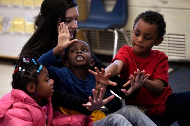 Paraprofessional Madison Marasco counts to 10 with kindergarten students Salah Osman, Za'Mayah Jones, and Deangelio Heard at Denver's Fairview Elementary.