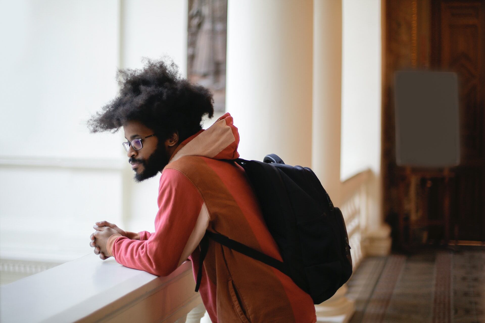Student wearing a backpack looking out over a banister.