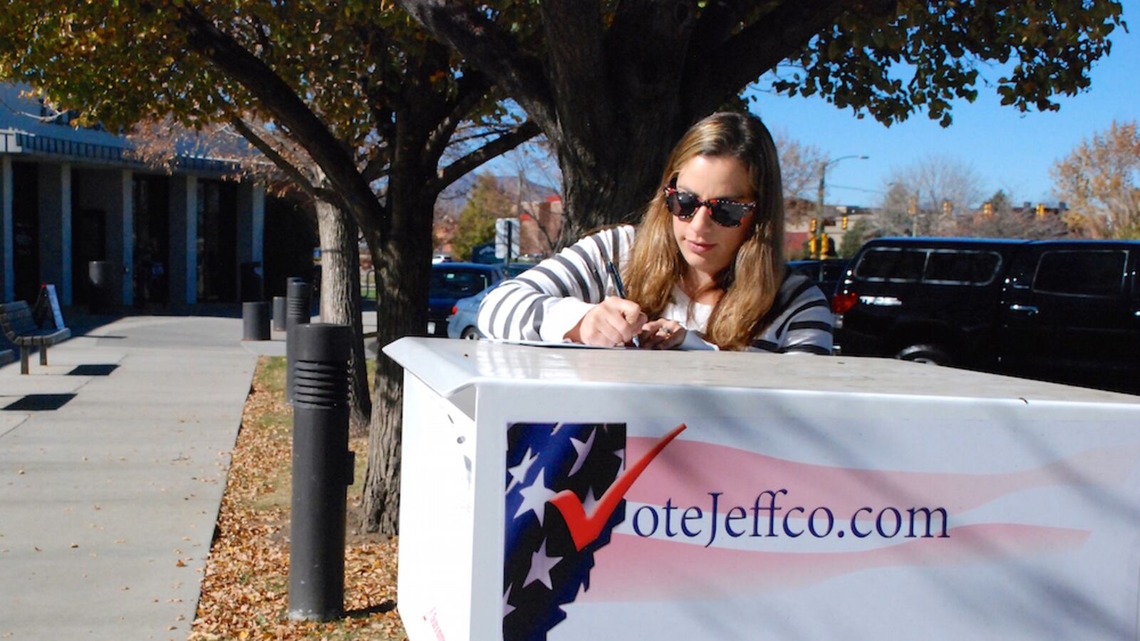 Meredith Van Deman signs the back of her 2014 mail-in ballot  outside the Columbine Library in Littleton before turning it in.