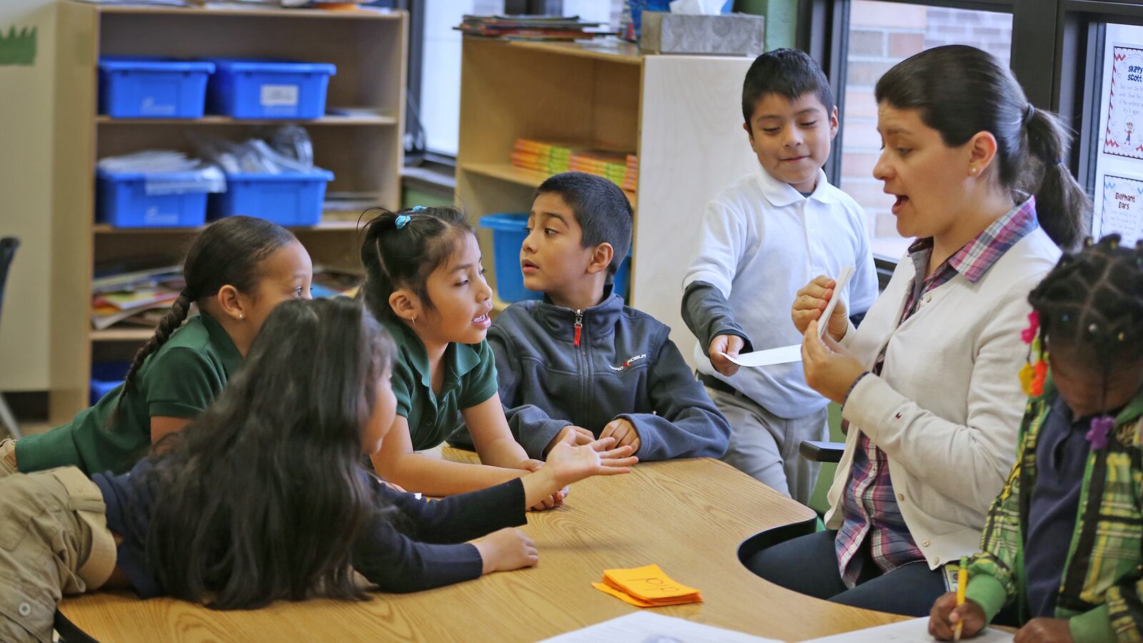 Instructional aid Maricela Berrospe, right, works with Kindergartners at Enlace Academy.  Much of the instruction at the school takes place in small groups.