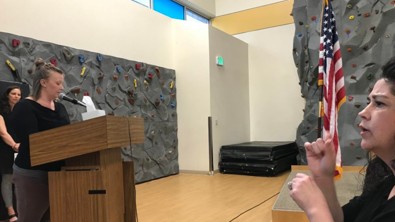 One sign language interpreter, on the right, interprets while another gives public comment to the Denver school board.