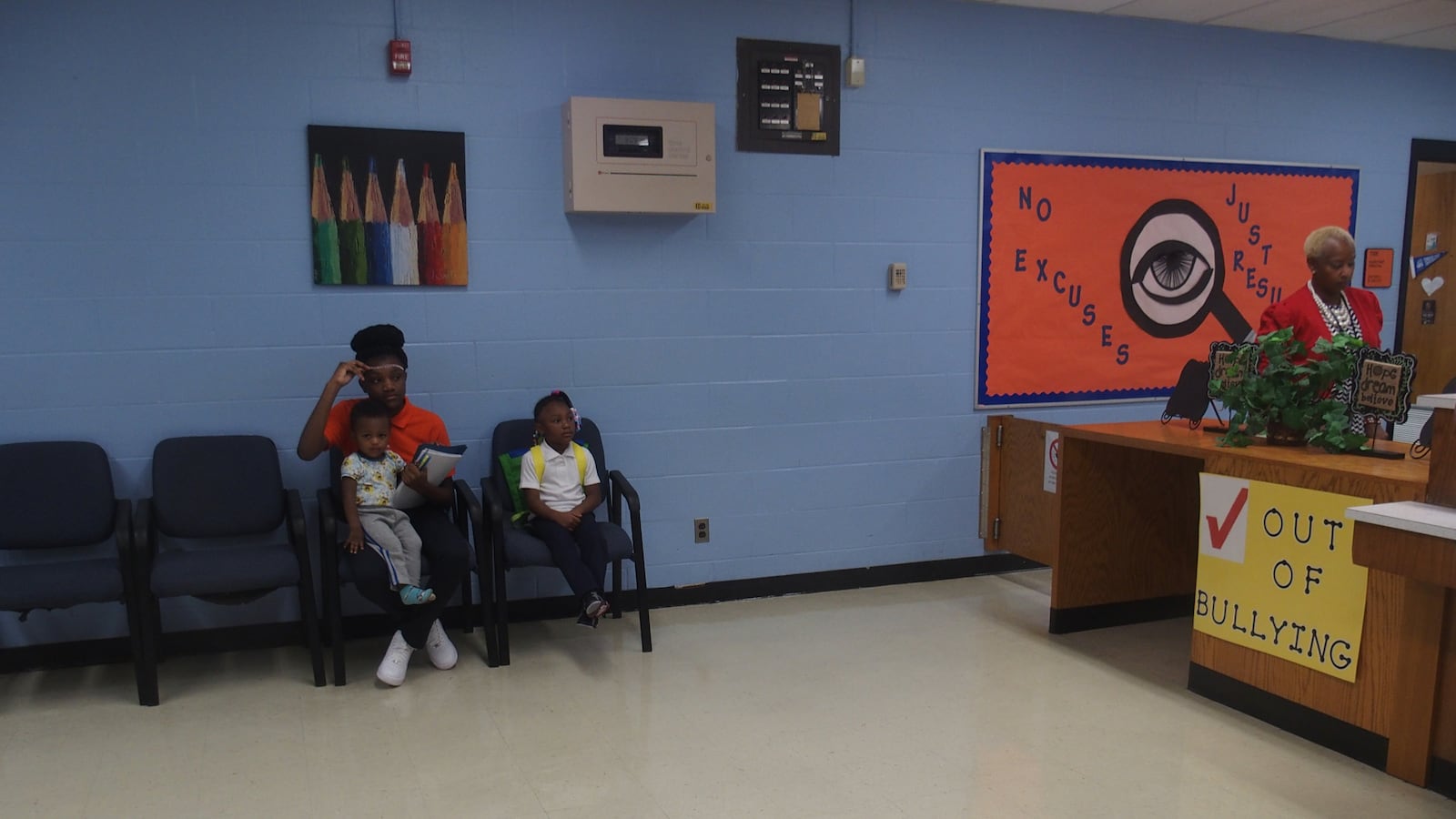 Alissiya, 6, and Tynesha, 13, wait with their mother to be registered for the first day of school.