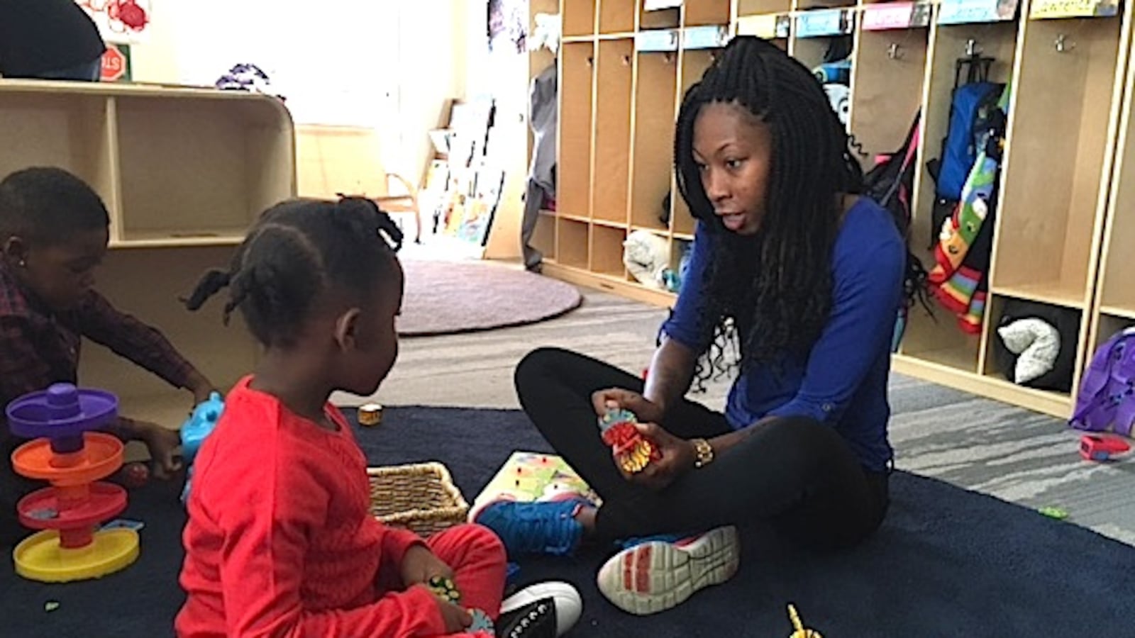 Assistant teacher E’Monna Moore plays with a child at the Sewall Child Development Center at the Dahlia Campus.