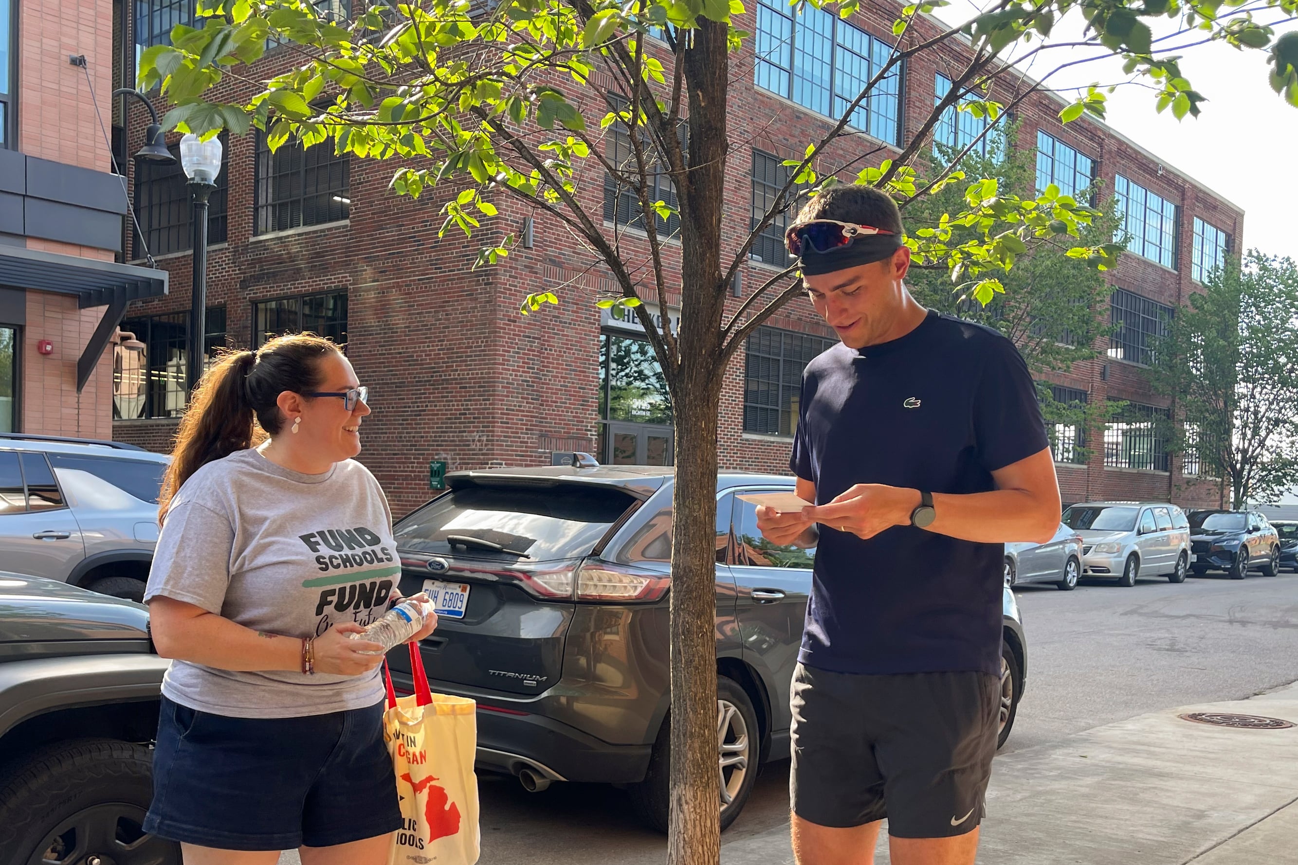 Two people are talking on a sidewalk.