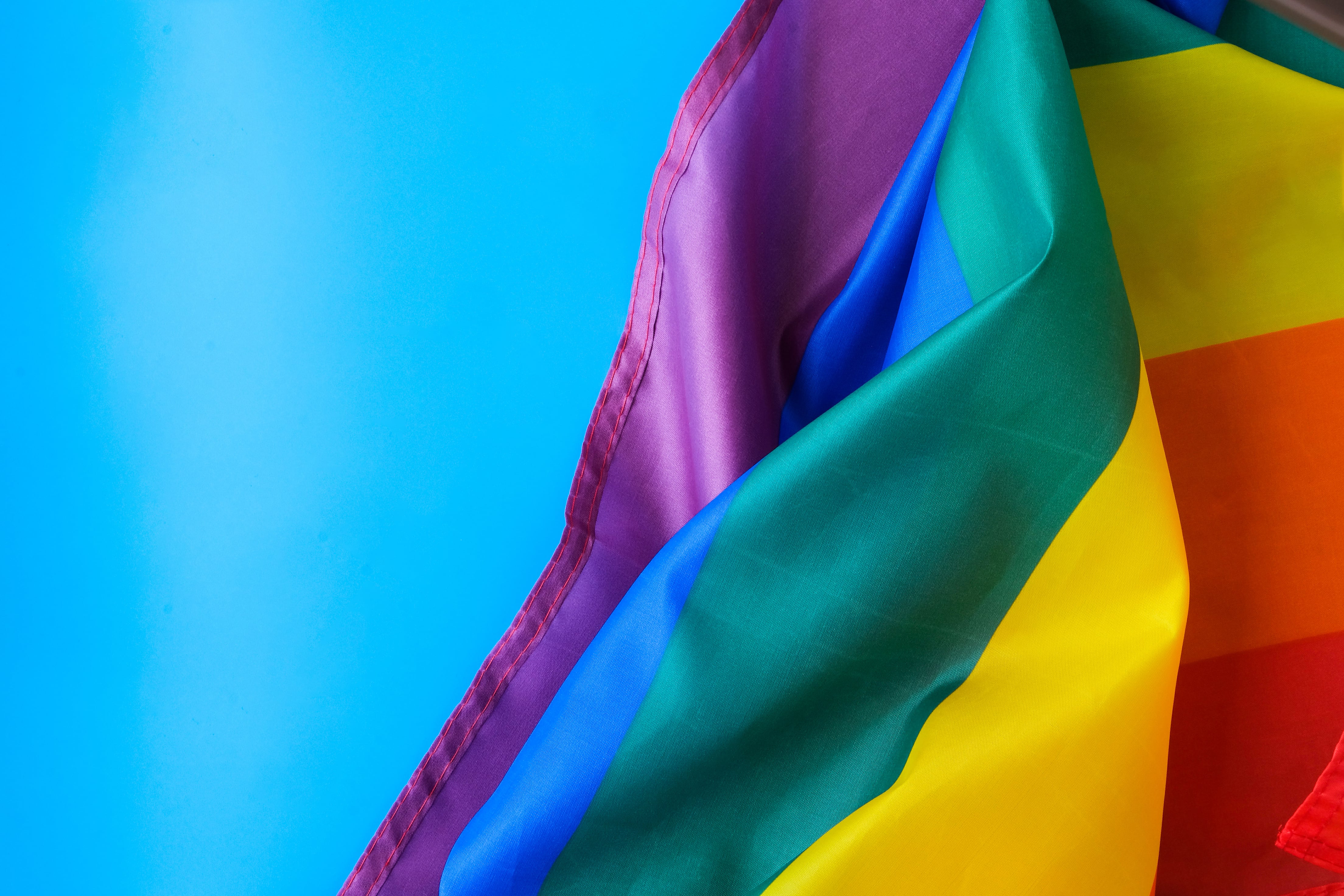 A rainbow flag against a blue sky.