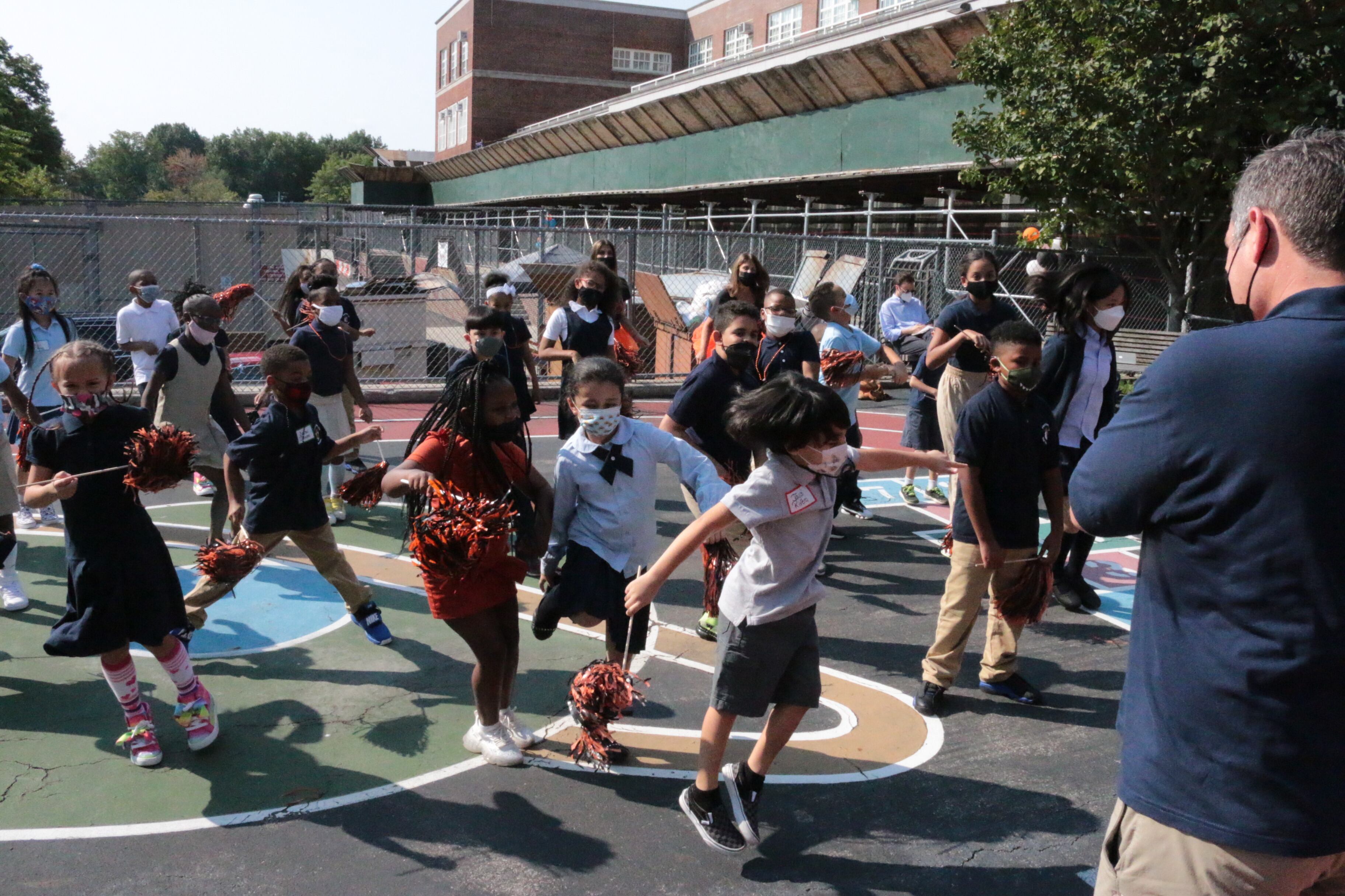 Students dance together on a blacktop playground on the first day of school in New York City.