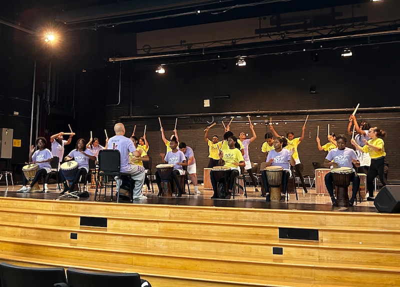 A group of students drum on stage.
