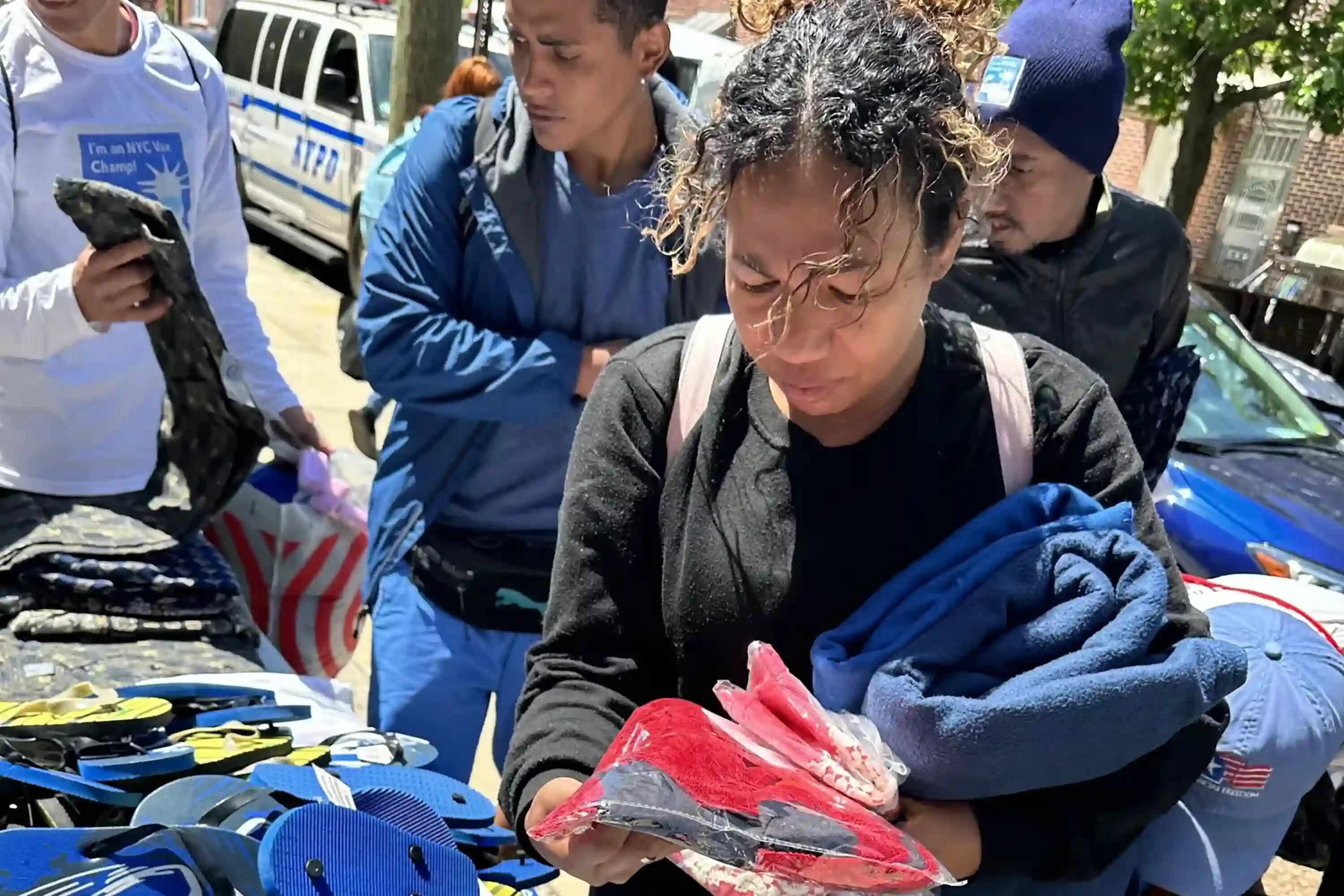 A woman in black and two men look through items at a clothing drive.