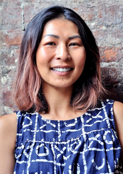 Headshot of a woman with dark hair, dyed at the ends, wears a blue and white top.