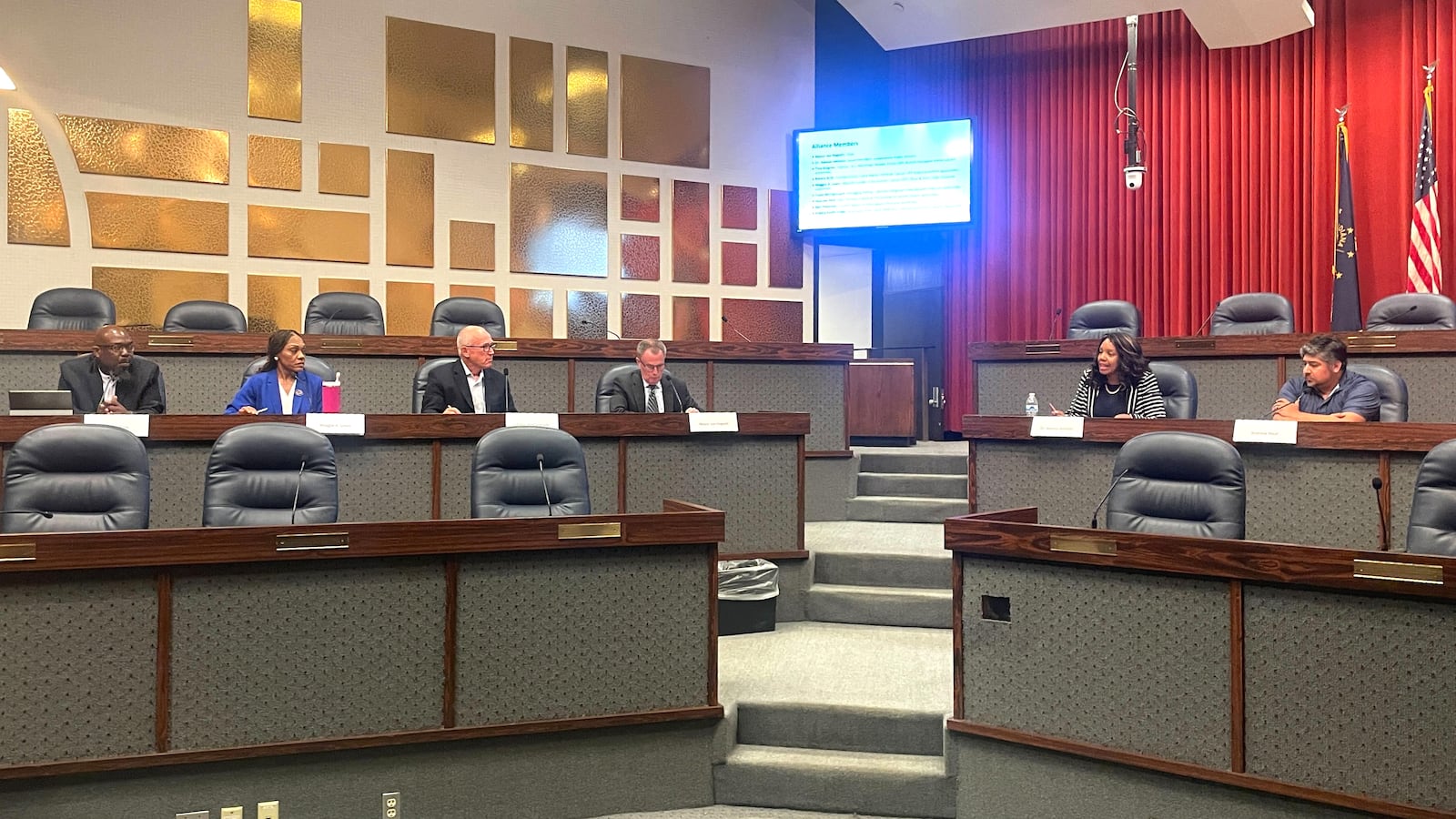 A group of men and women sit at the front of a meeting room.