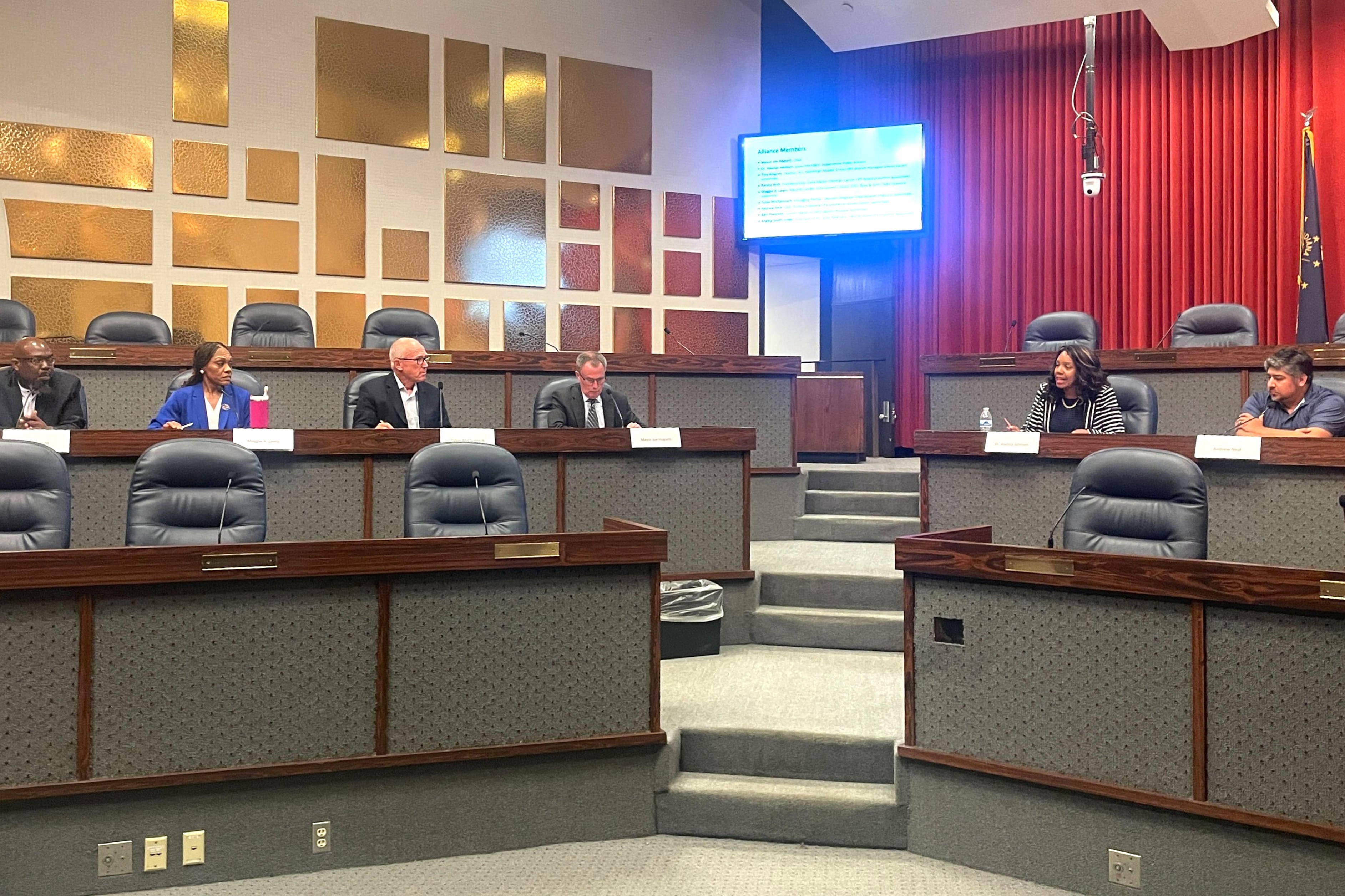 A group of men and women sit at the front of a meeting room.