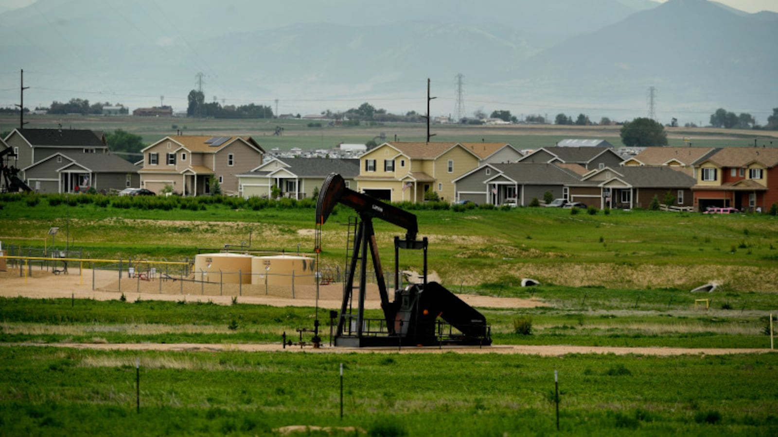 An oil derrick pumps oil near a subdivision roundabout in Dacono.
