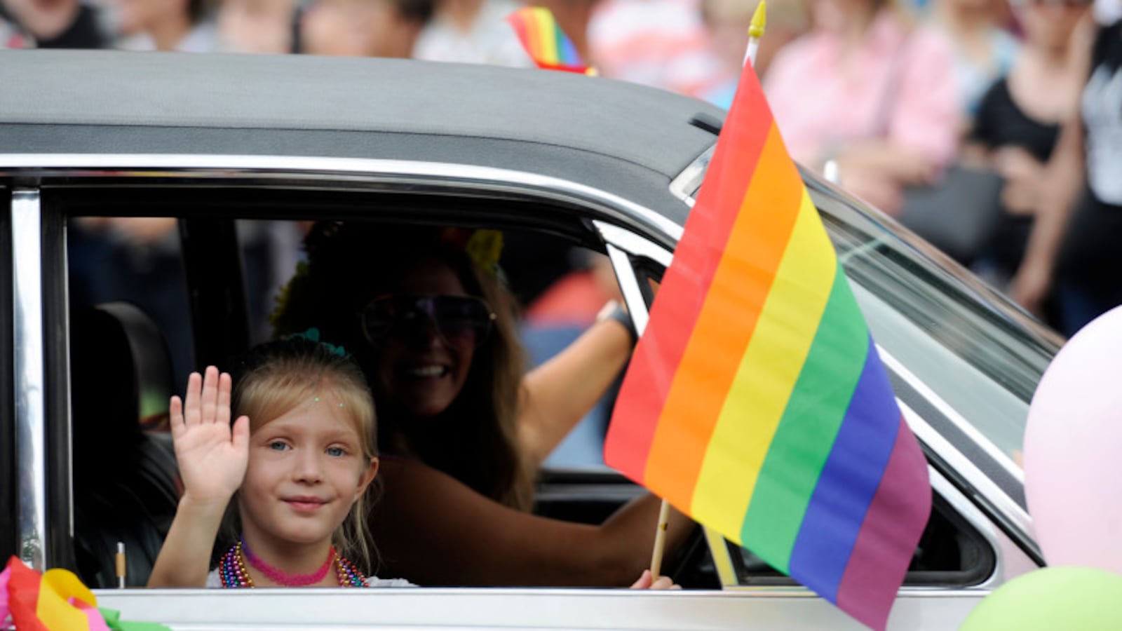 A child waves a a rainbow flag out of a window during the Denver Pride Parade along Colfax Avenue in 2018.